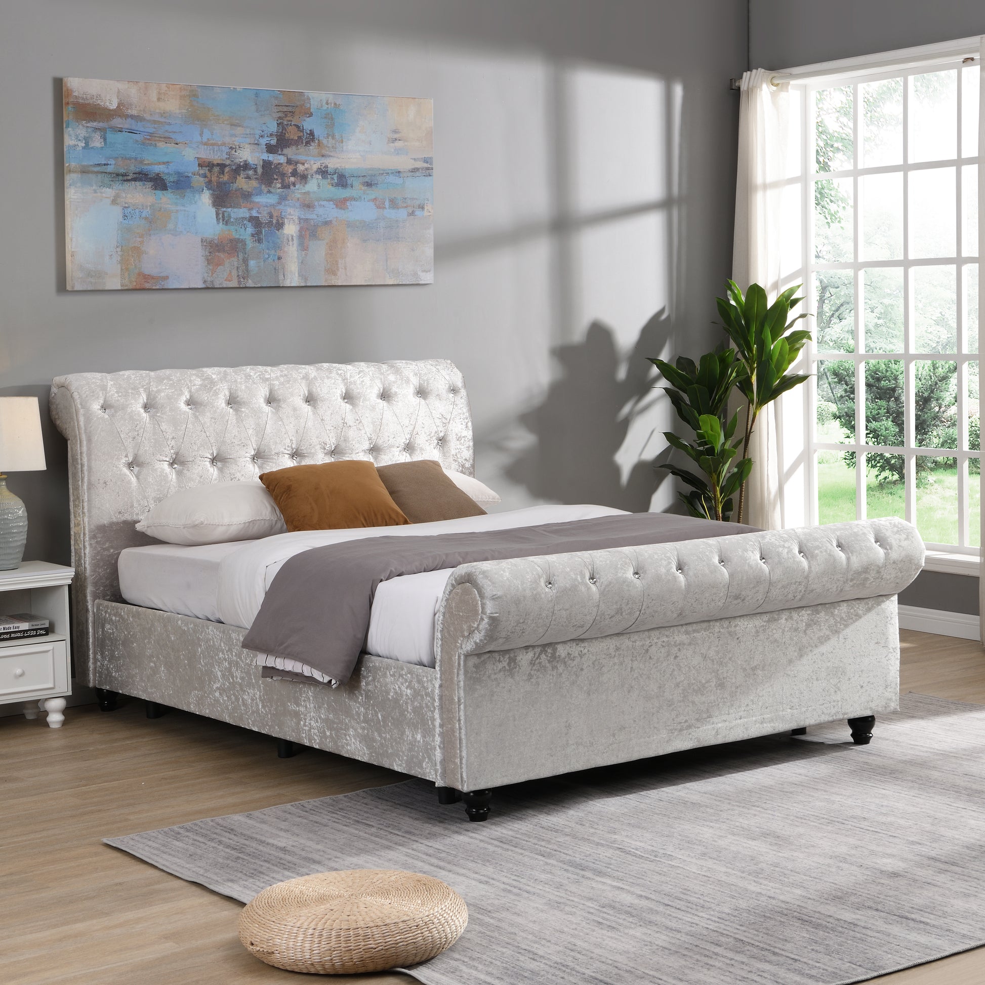 Luxurious crushed velvet sleigh bed in a light silver featuring deep button tufting on the headboard and footboard