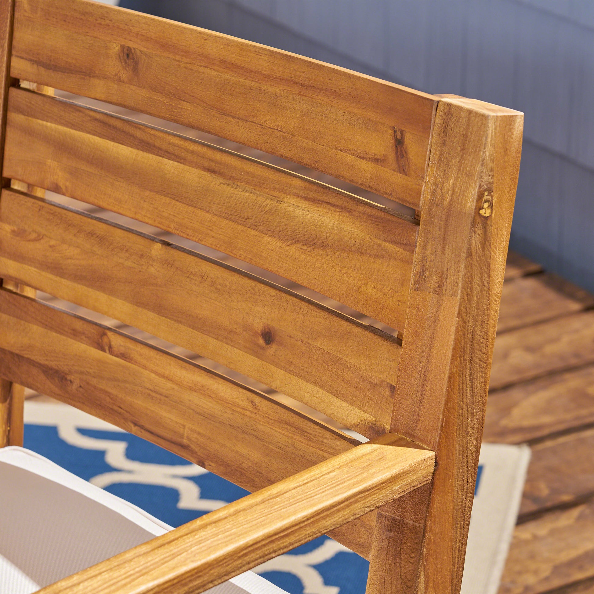 Closeup of natural acacia wood slats on an outdoor patio chair showing wood grain