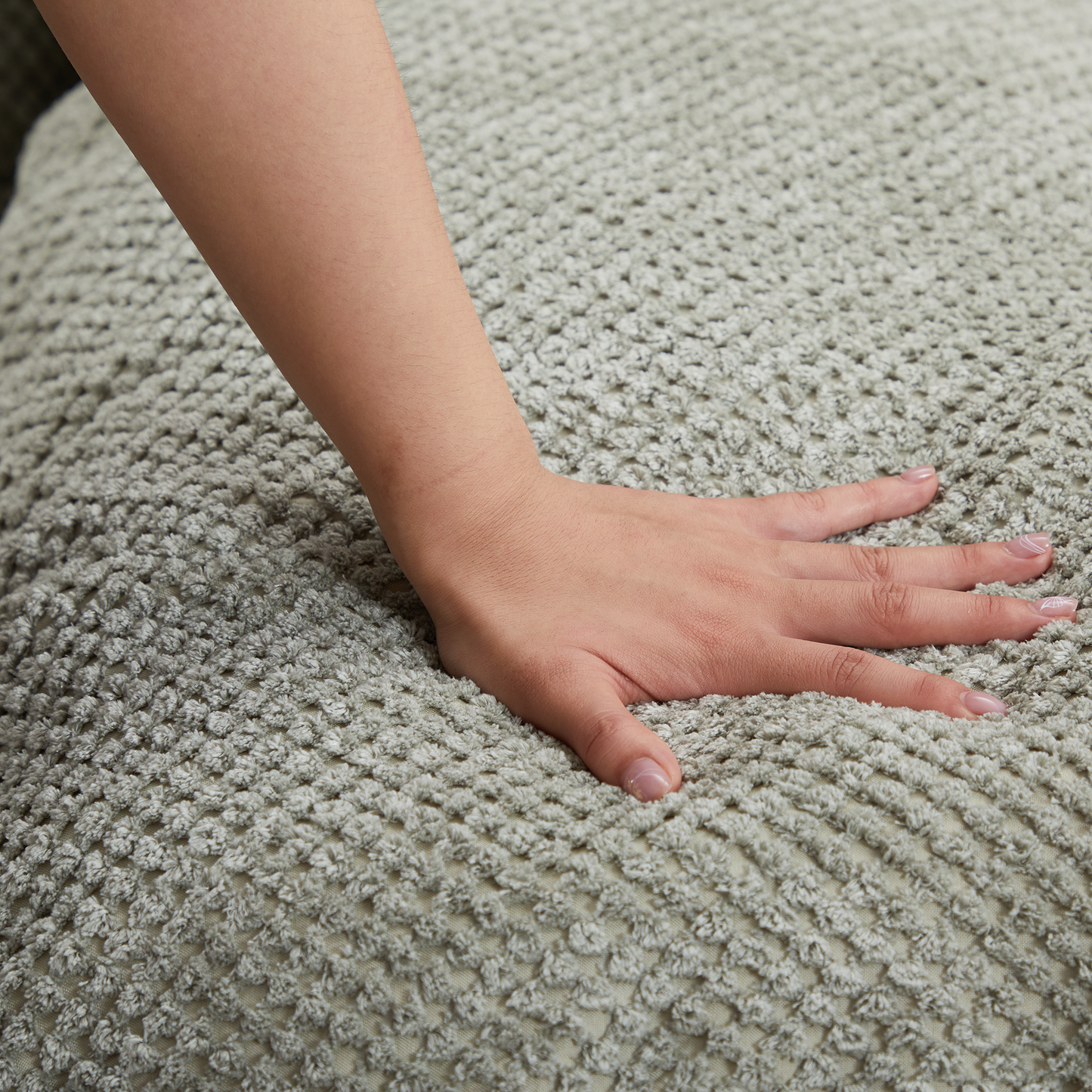 Hand pressing into soft textured grey cushion for comfort demonstration