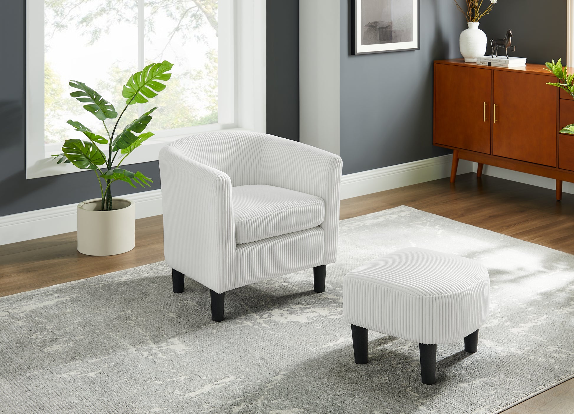 White corduroy accent chair with matching ottoman on a gray abstract rug