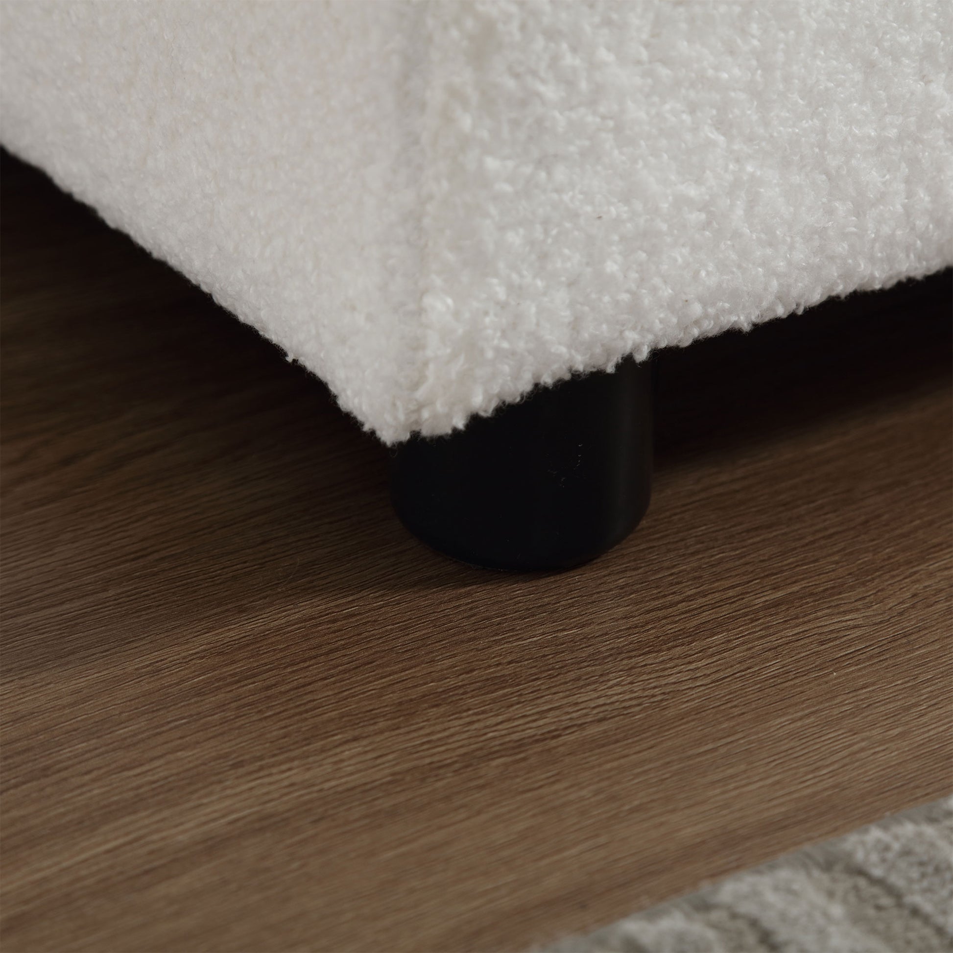Closeup of plush white teddy fabric on a sofa leg warm wooden floor