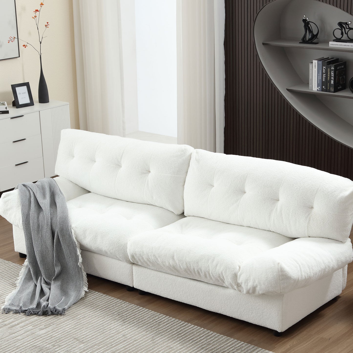 Plush white boucl sofa with deep tufted cushions and a gray throw blanket
