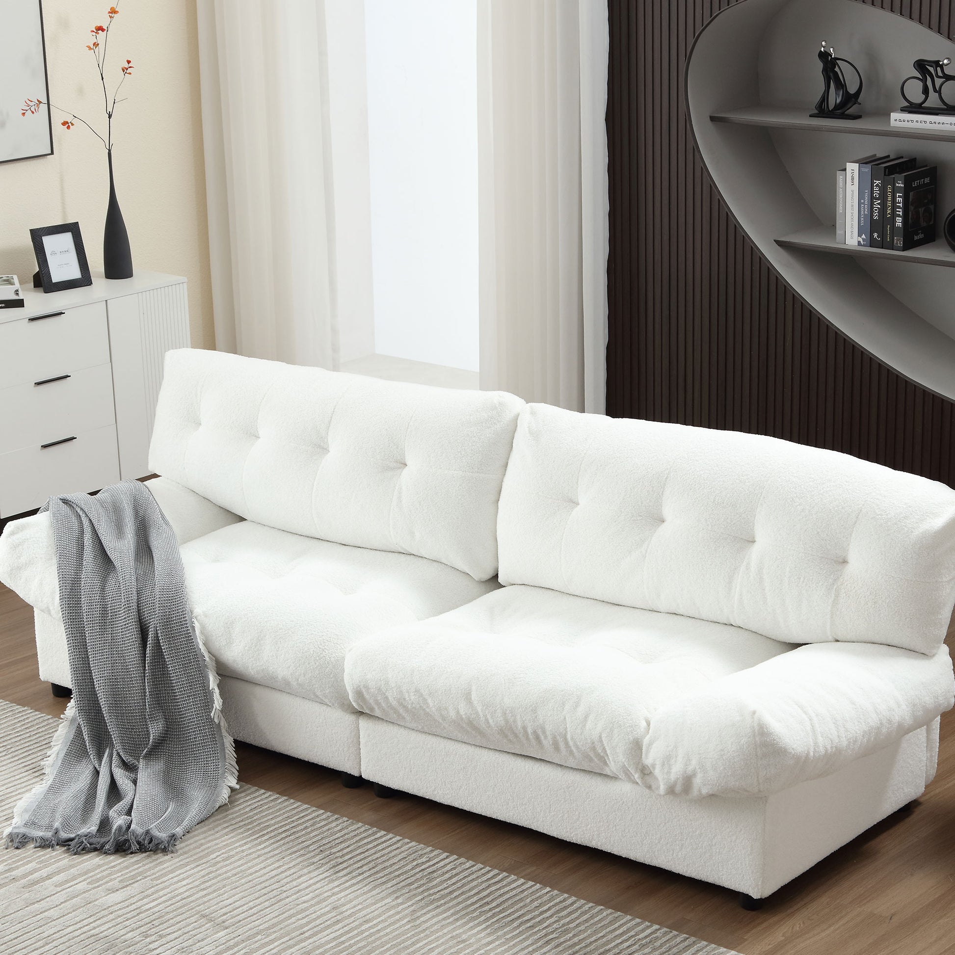 Plush white boucl sofa with deep tufted cushions and a gray throw blanket