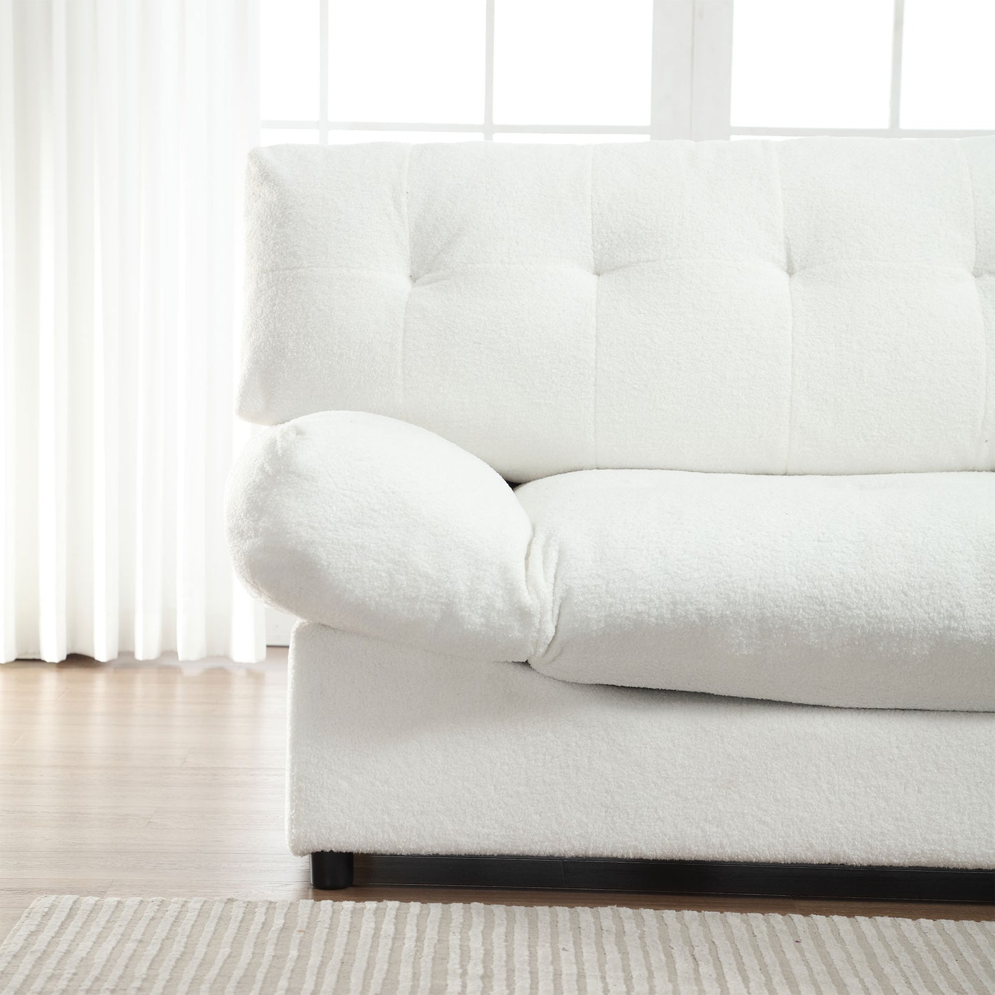 Closeup of a tufted white boucle sofa with plush armrest detail perfect for cozy living rooms
