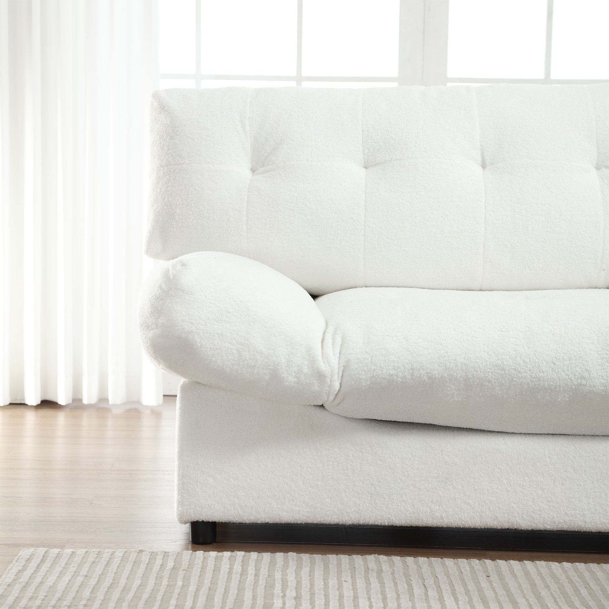 Closeup of a tufted white boucle sofa with plush armrest detail perfect for cozy living rooms