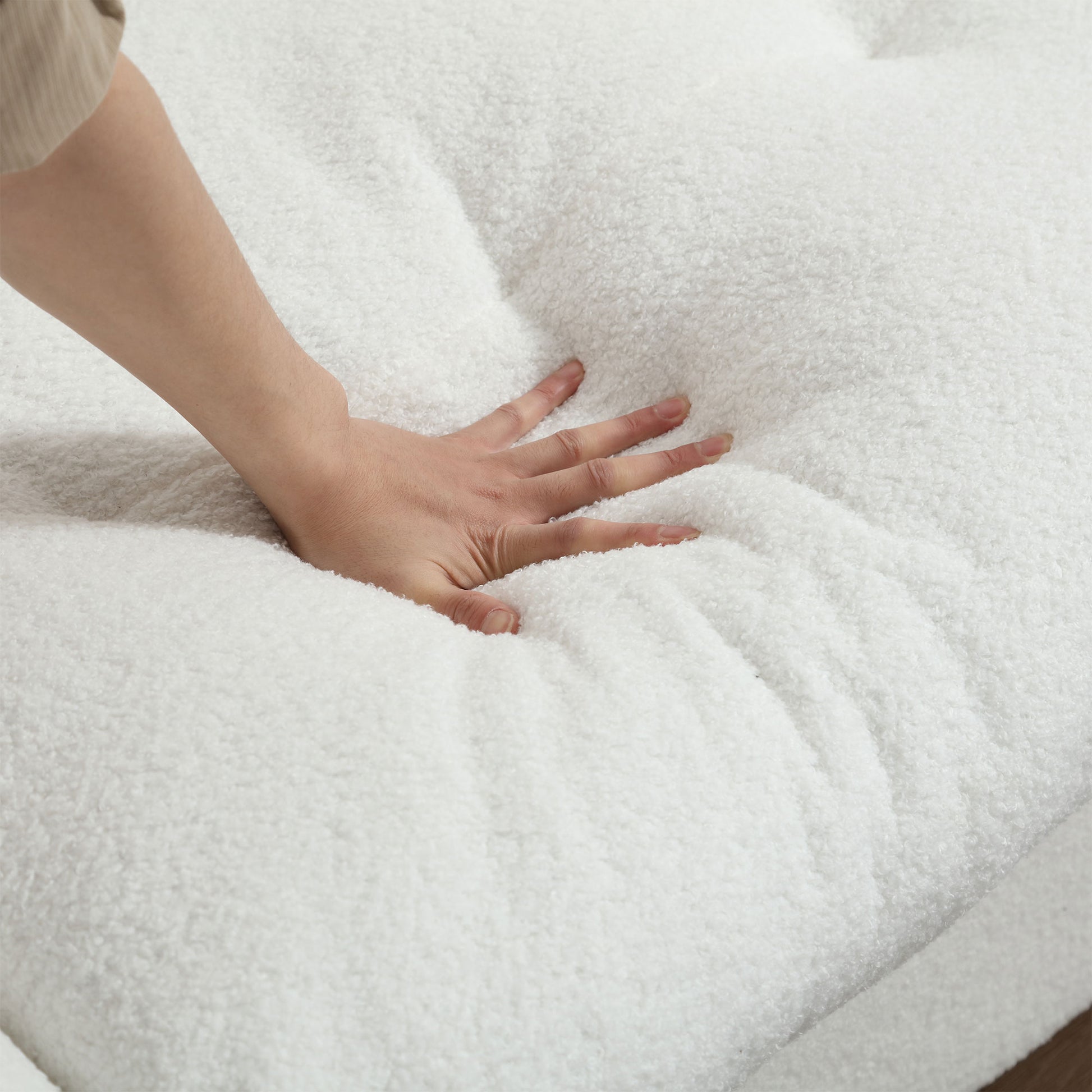 Closeup of a hand pressing into soft white sherpa fabric for a cozy couch