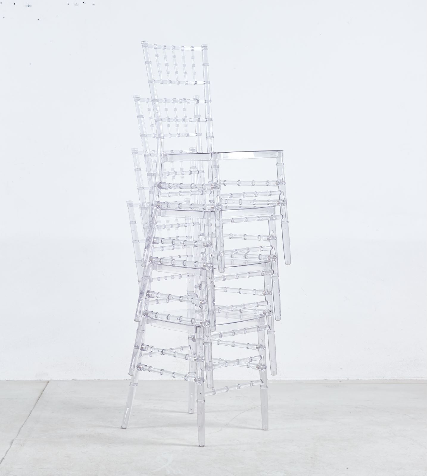 Stack of clear acrylic ghost chairs with intricate detailing
