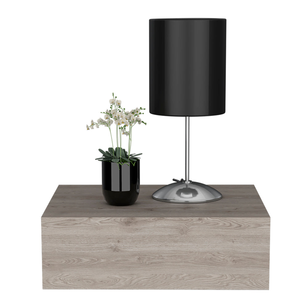Black cylinder shade table lamp with chrome base on woodgrain shelf beside potted orchid