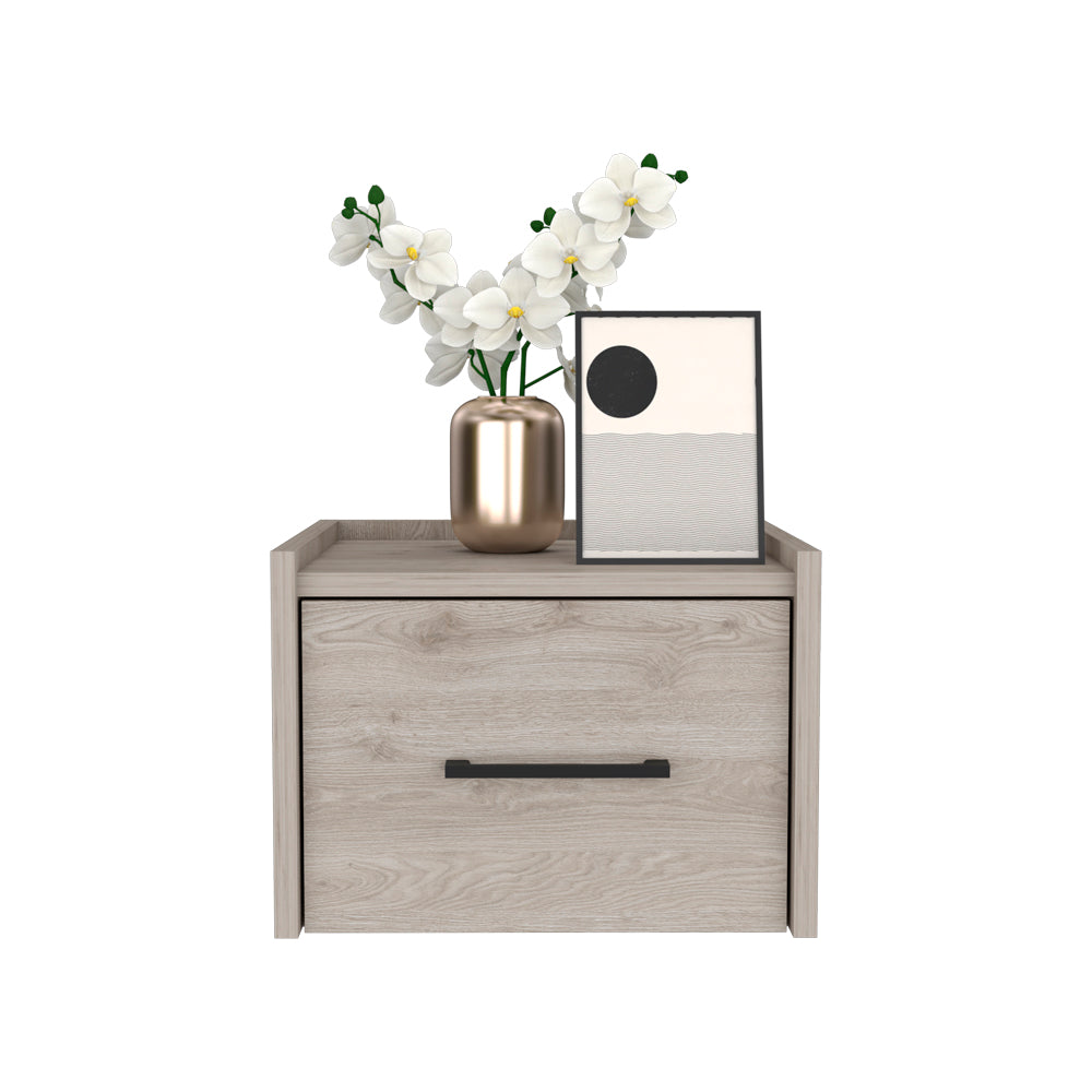 Light wood bedside table with black handle and gold vase holding white orchids