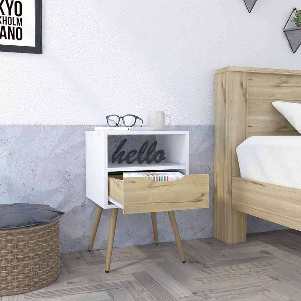White nightstand with a wood drawer and angled legs next to a bed