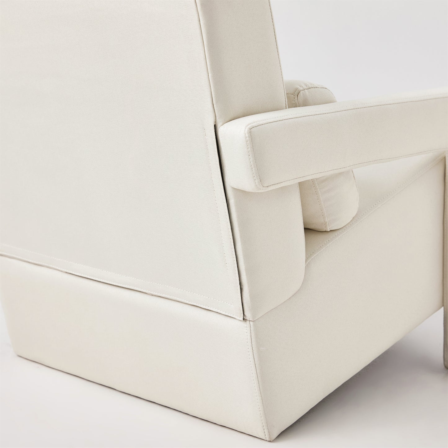 Closeup of a cream fabric armchair showing its modern design and stitched details