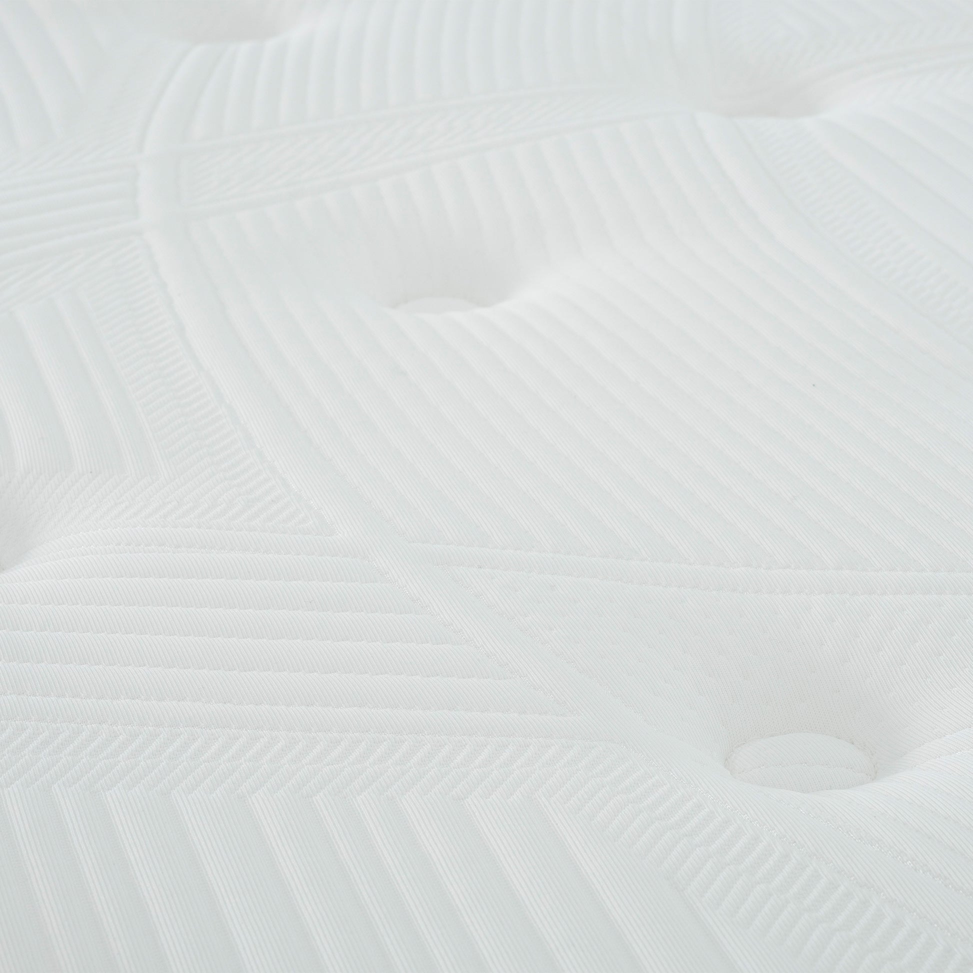 Closeup of a white quilted mattress surface with tufted buttons and geometric stitching details