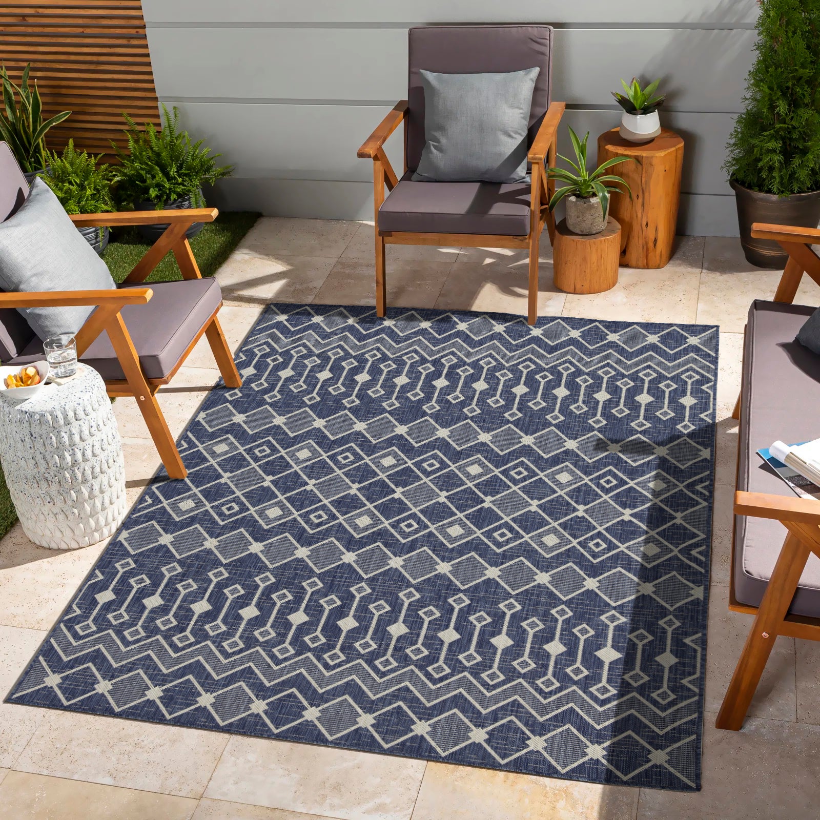 Navy geometric outdoor rug with a diamond and zigzag pattern on a patio