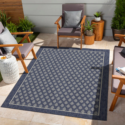 Navy blue outdoor rug with a geometric diamond pattern and light accent border