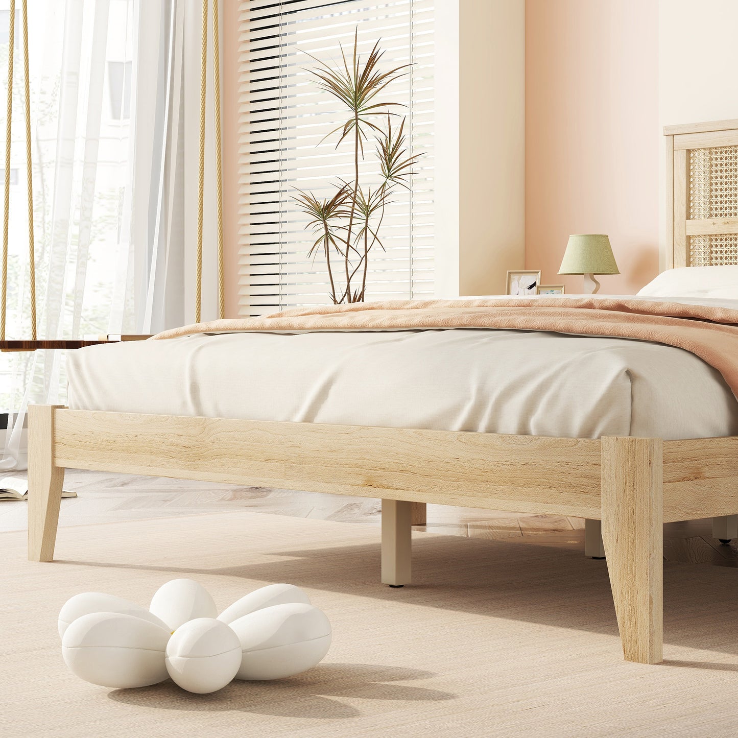 Natural wood platform bed frame with white linens and a peach throw