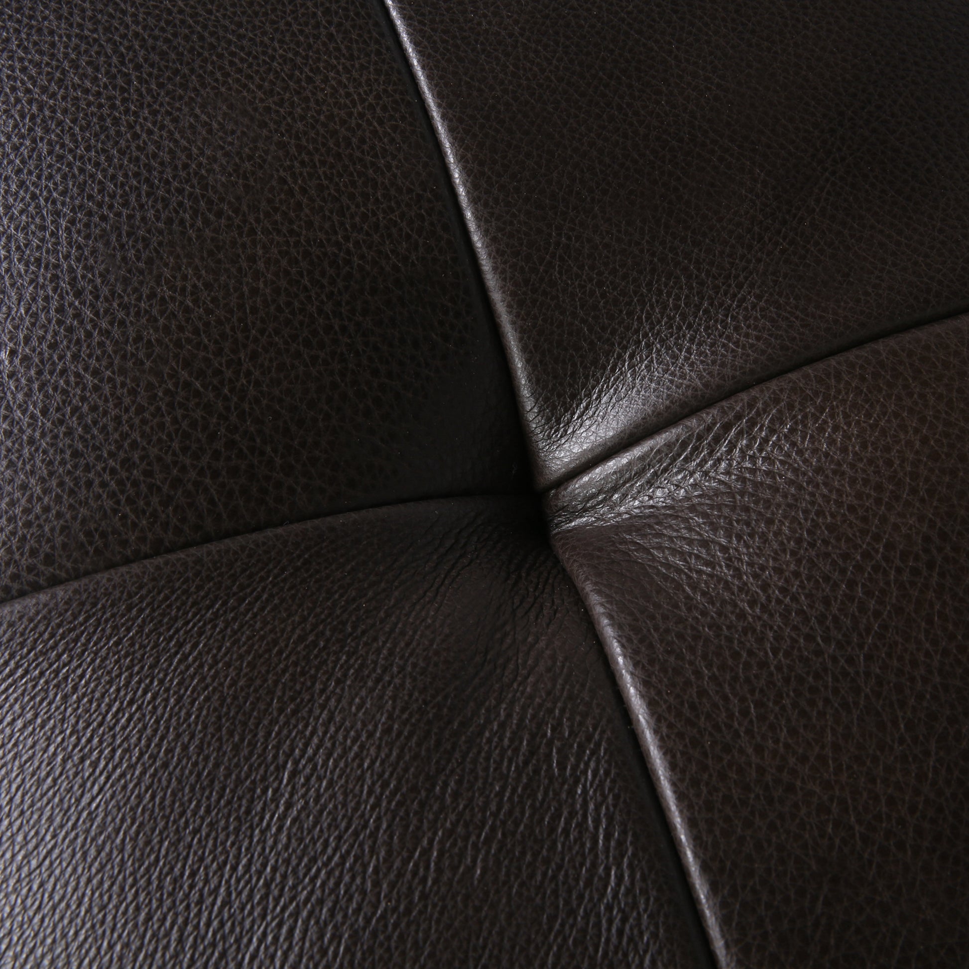 Closeup of rich dark brown leather with a subtle quilted pattern and visible grain
