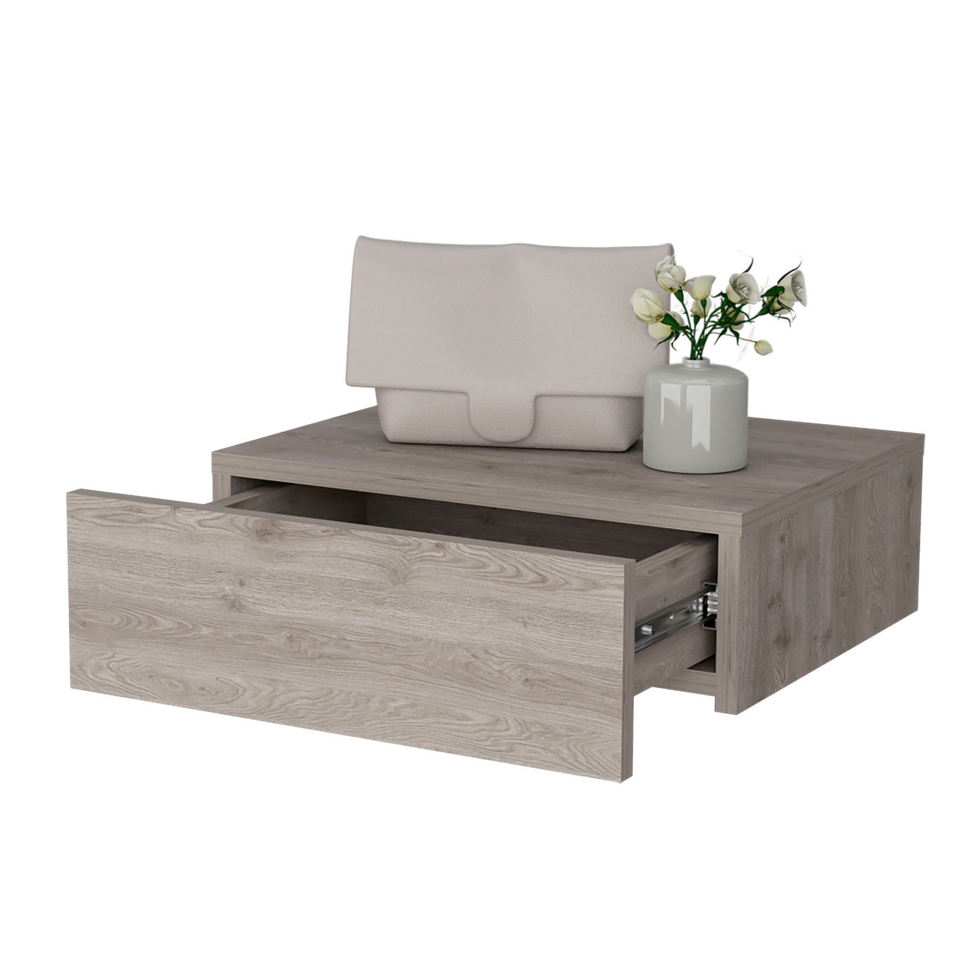 Modern grey wood floating nightstand with open drawer displaying drawer slides a beige clutch bag and a vase of white flowers
