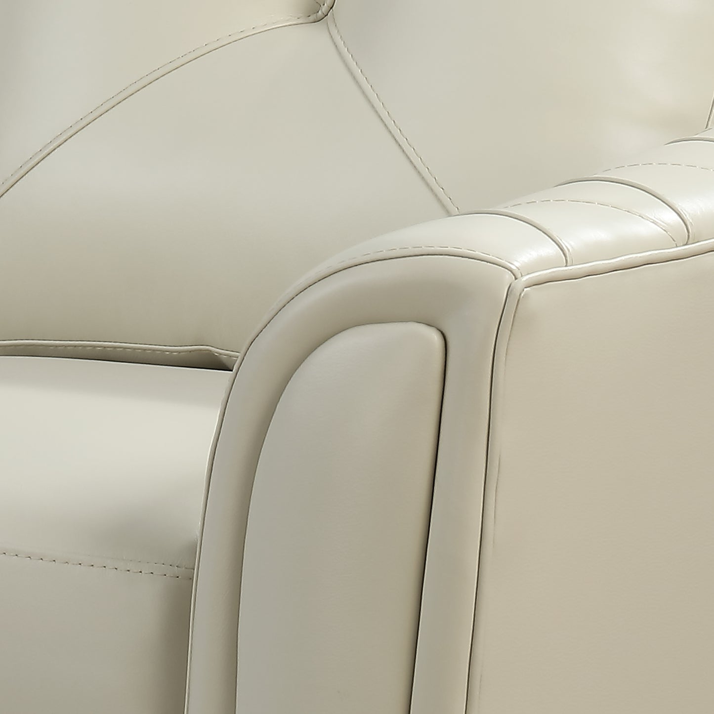 Closeup of a plush cream leather armchair armrest with elegant tufting and detailed stitching