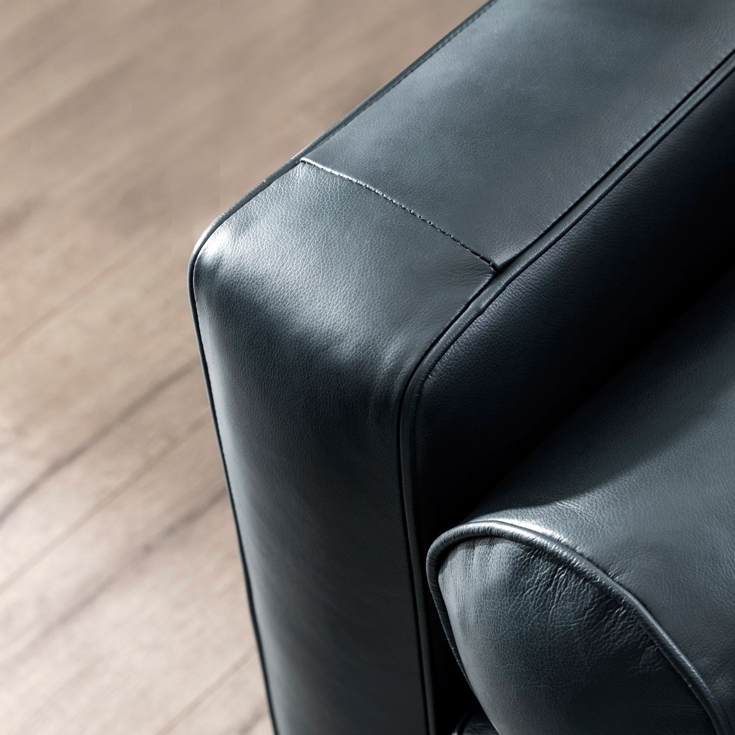 Detail of a sleek black leather armchair showing its textured material and stitching