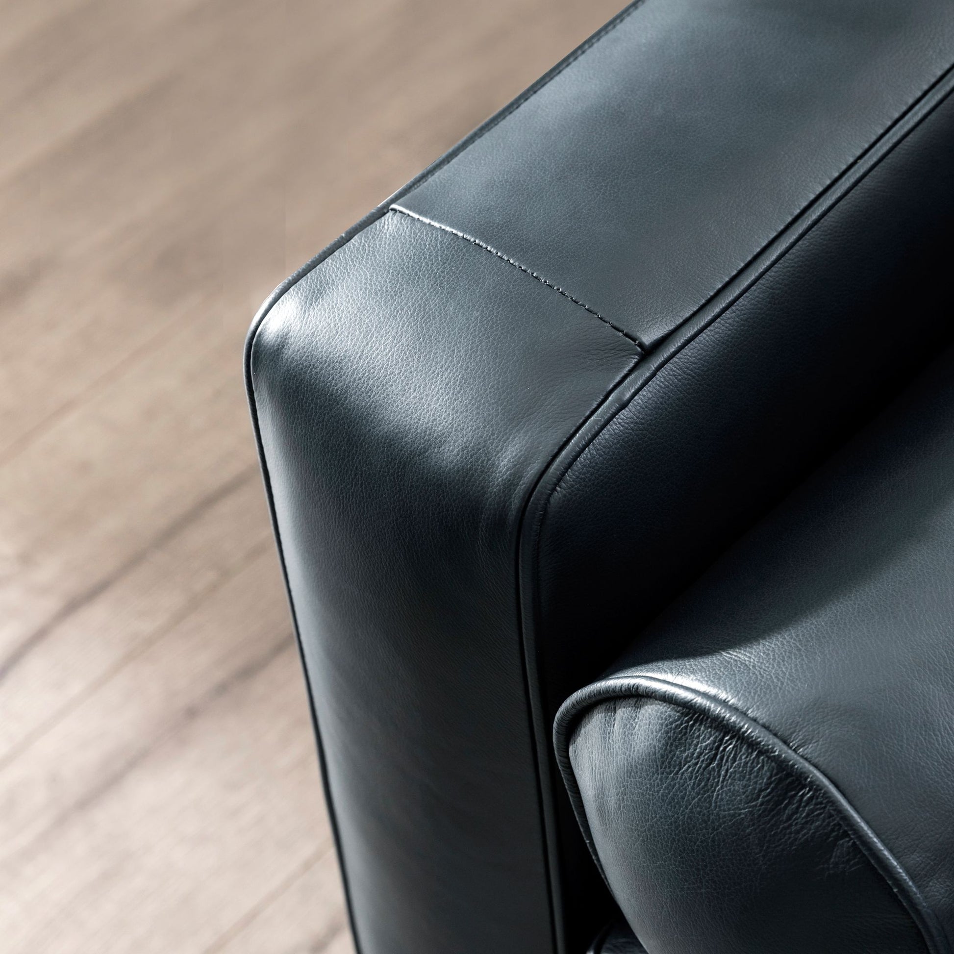 Detail of a sleek black leather armchair showing its textured material and stitching