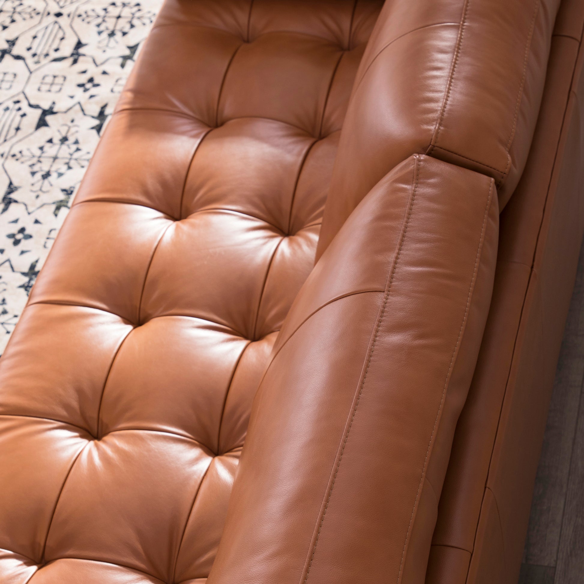 Closeup of tufted camel leather sofa armrest with detailed stitching