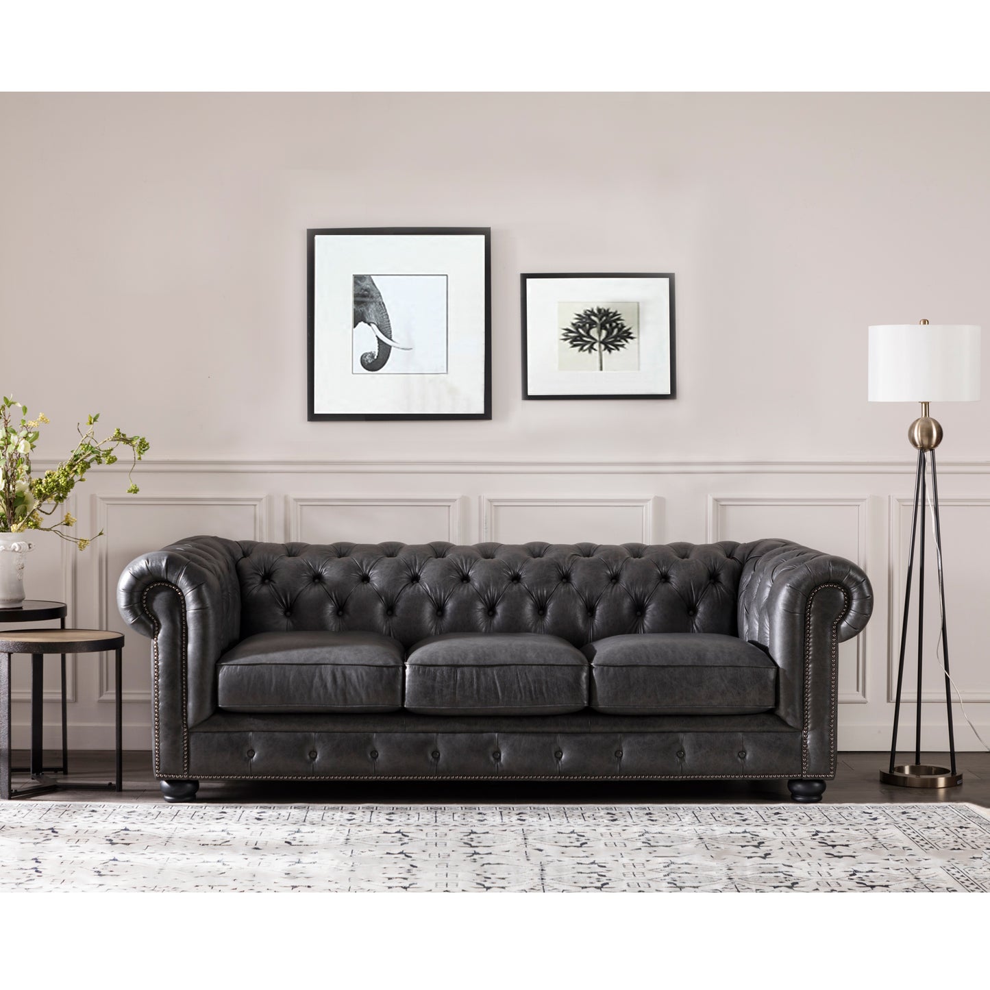 Dark grey tufted leather chesterfield sofa with rolled arms and brass nailhead trim