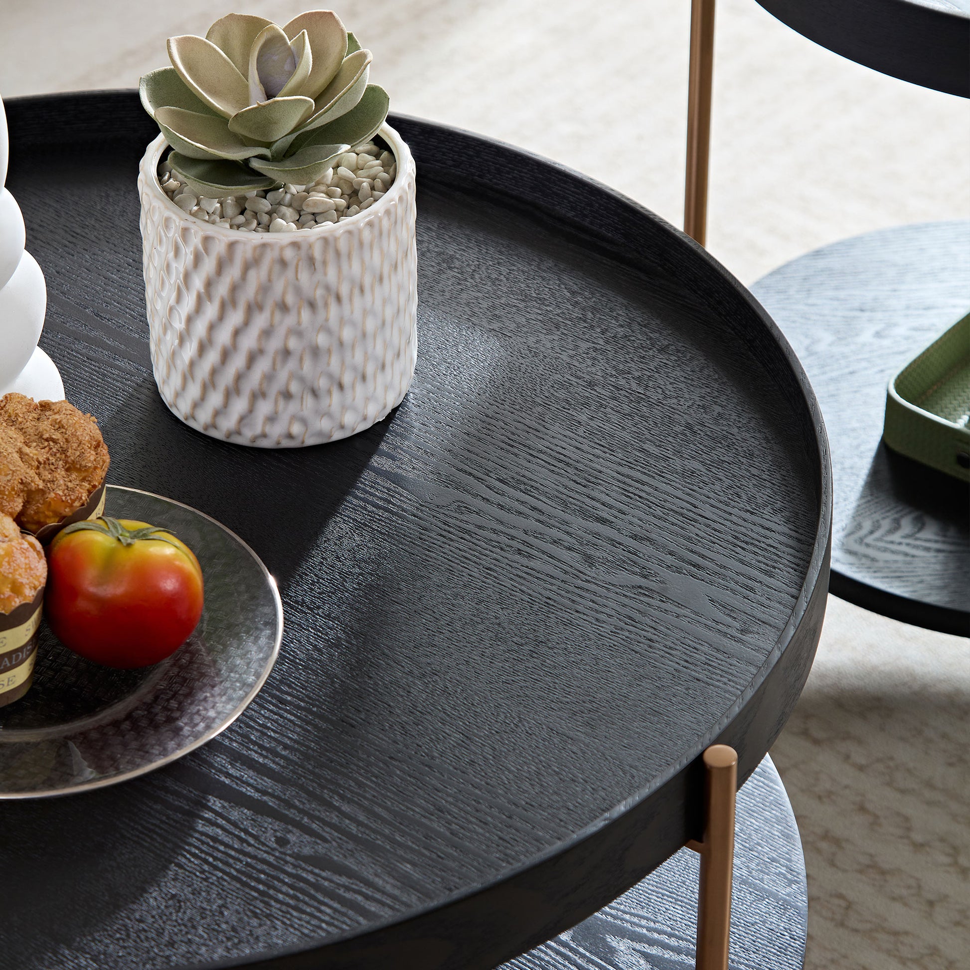 Black round wooden tray with faux succulent in textured pot and two muffins
