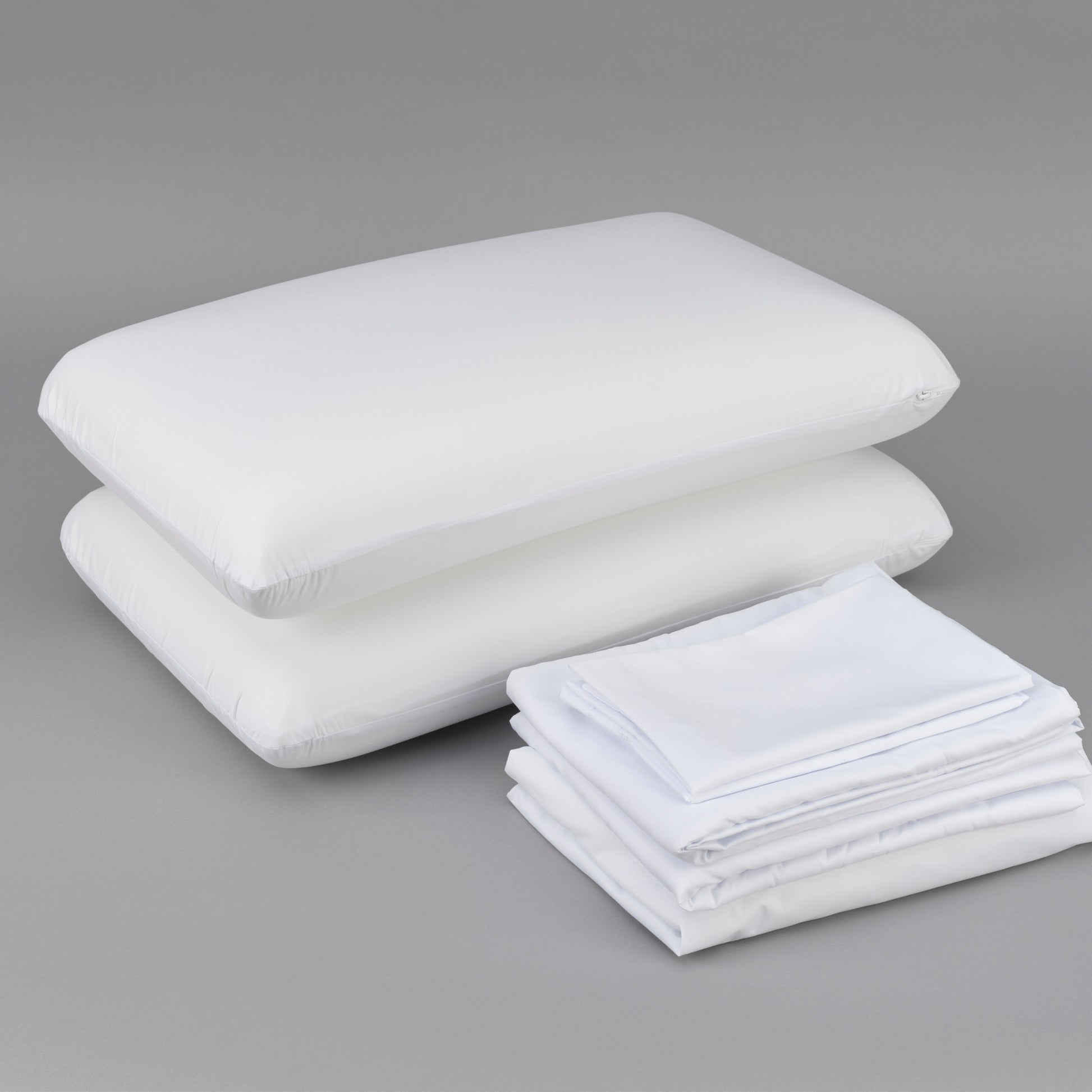 Stack of two white pillows and neatly folded white sheets perfect for bedding sets