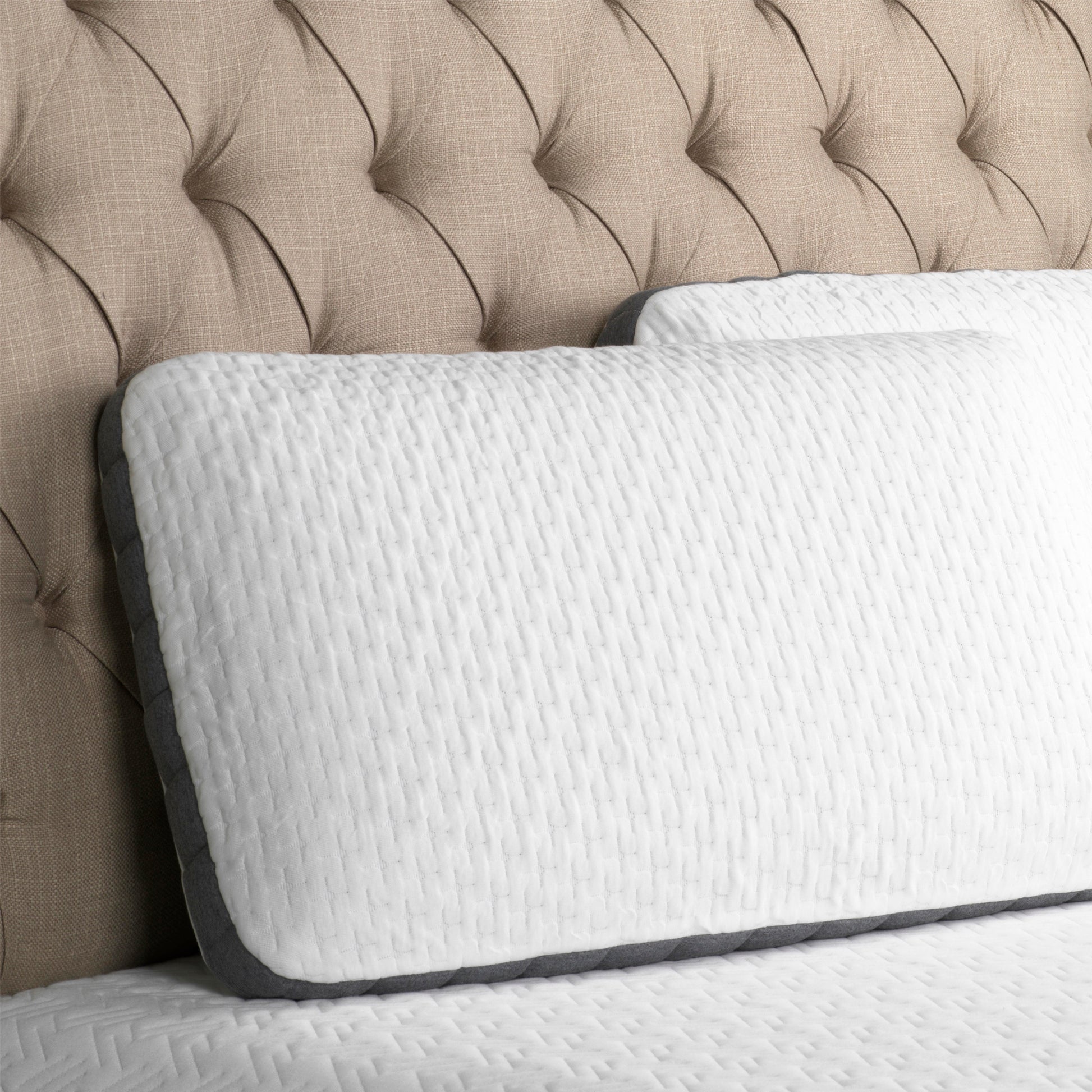 White quilted mattress with gray trim and beige tufted headboard