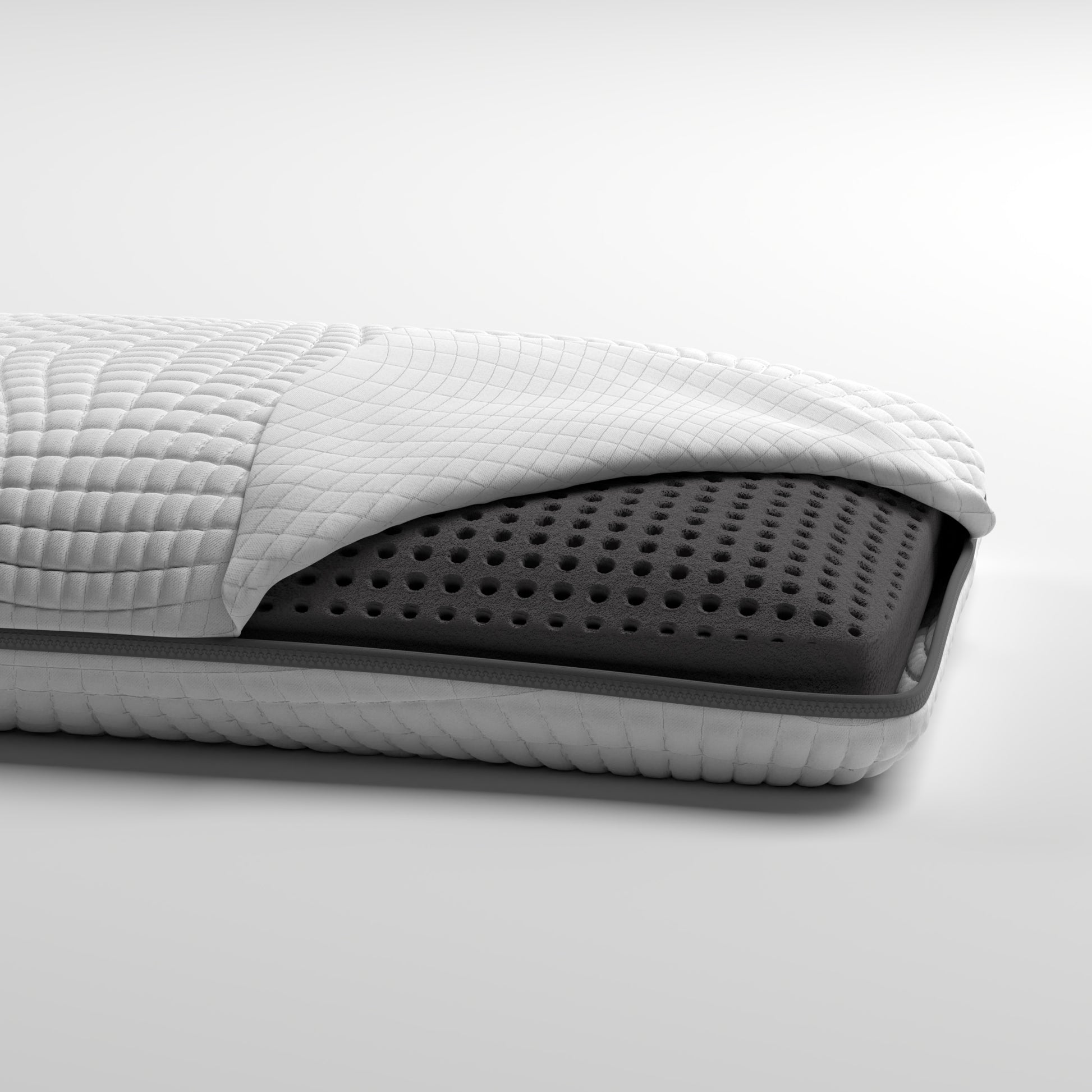 Crosssection of a memory foam mattress showing quilted white cover and dark grey perforated foam layer