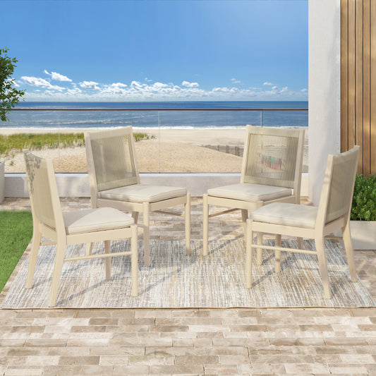 Four beige dining chairs with woven backs on an outdoor patio by the beach