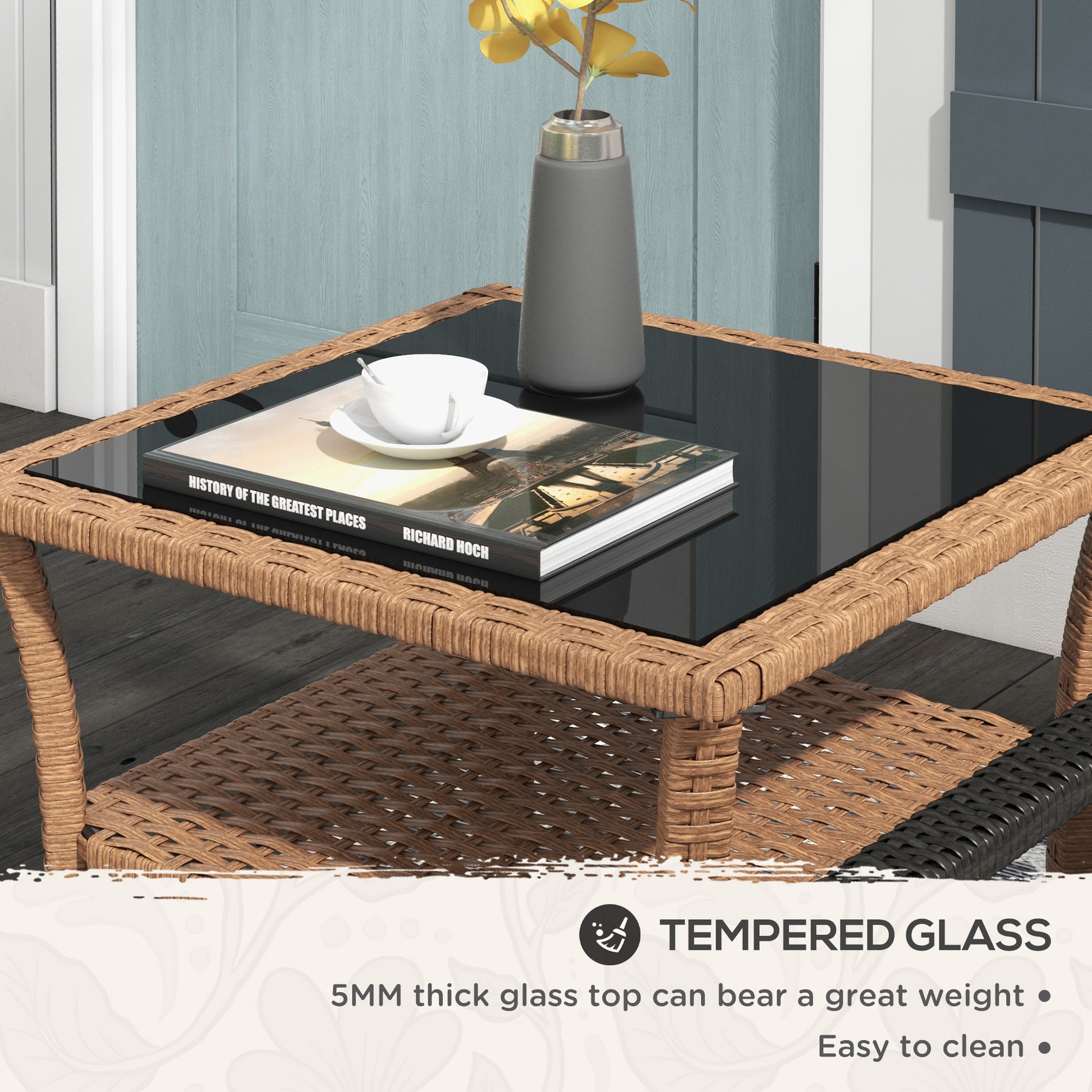 Wicker coffee table with tempered glass top holding a book and coffee cup