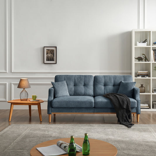 Tufted blue corduroy sofa with throw pillows and dark grey blanket