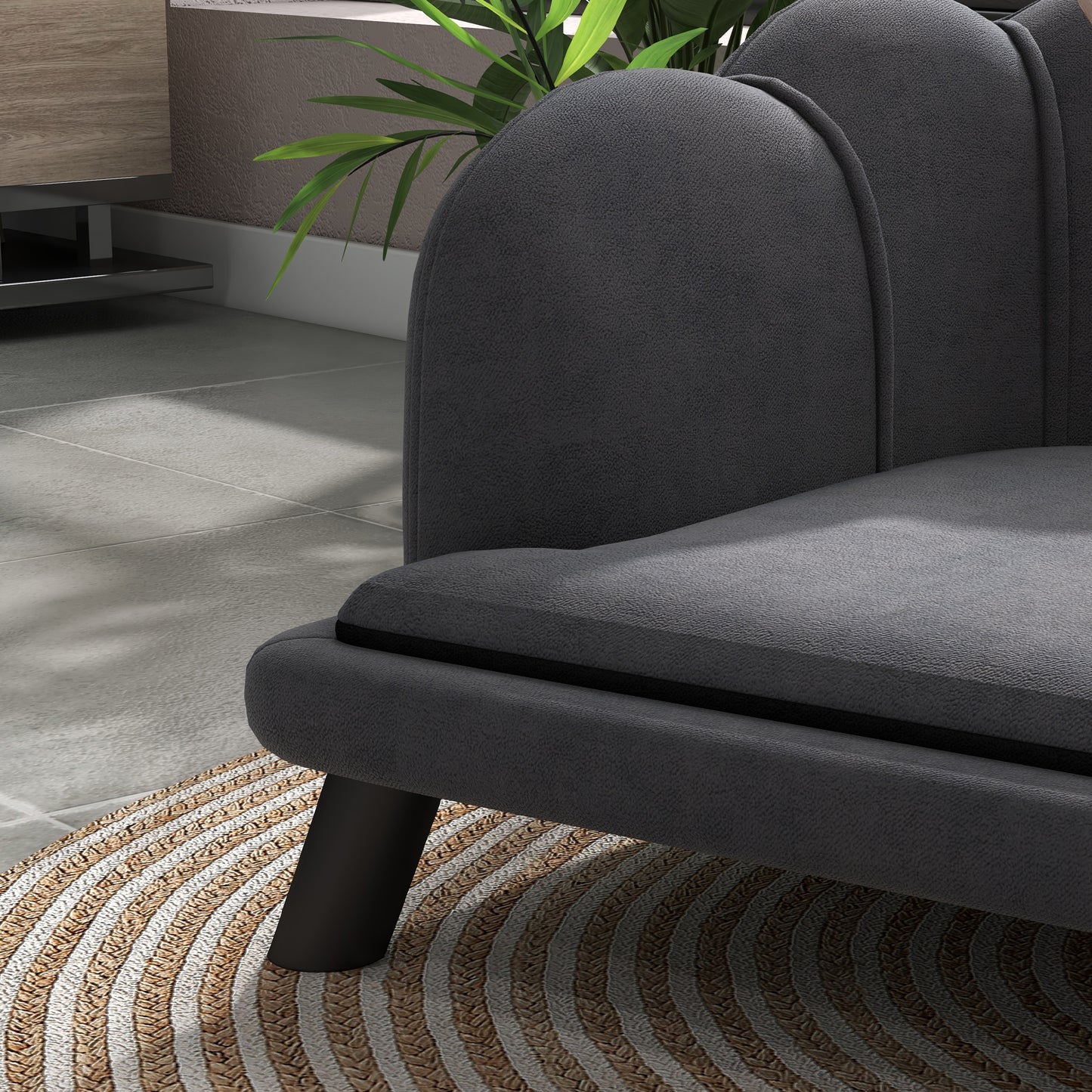 Dark gray upholstered armchair with curved backrest and black legs on a jute rug