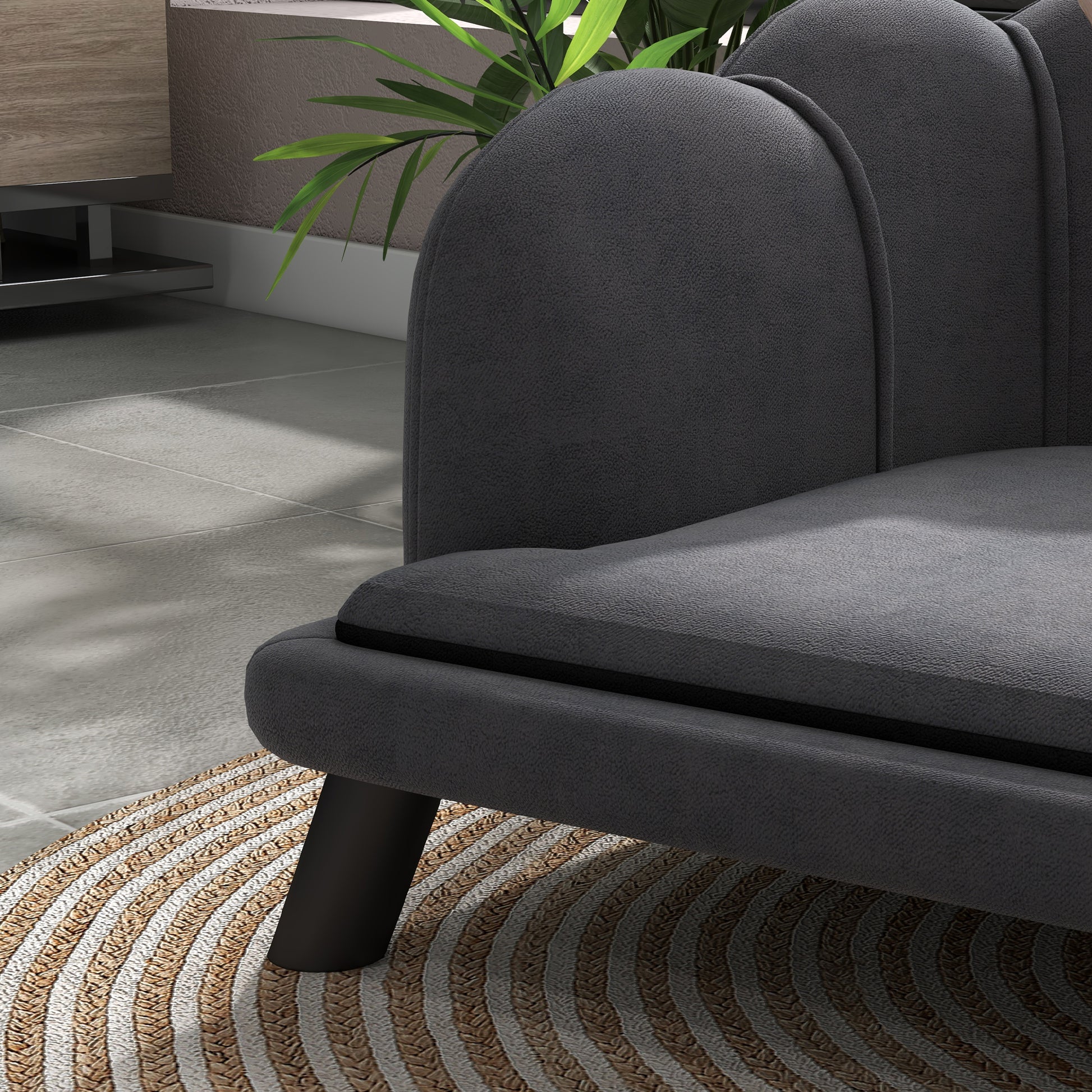 Dark gray upholstered armchair with curved backrest and black legs on a jute rug
