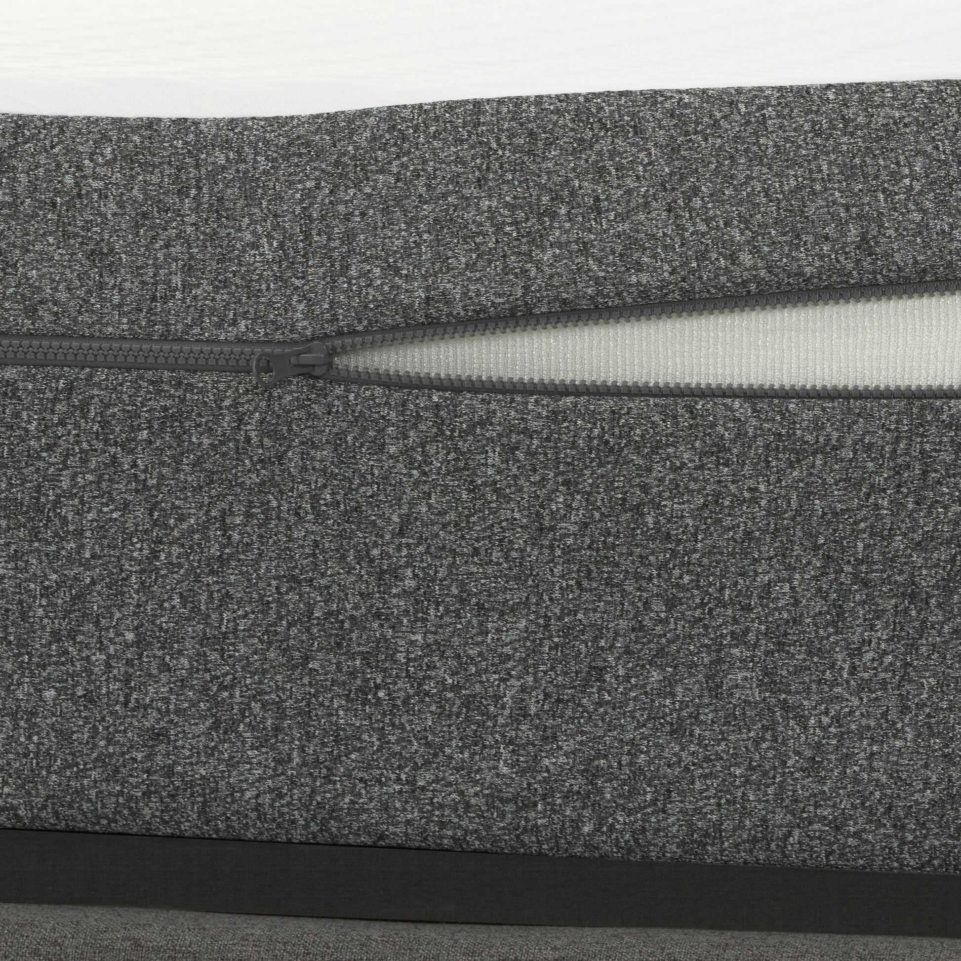 Closeup of textured charcoal grey fabric with a partially open zipper detail on a sofa