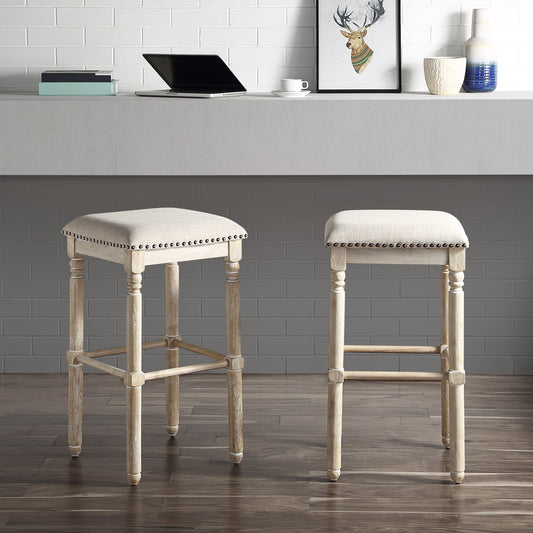 Upholstered beige linen bar stool with nailhead trim and distressed wood frame perfect for a kitchen island