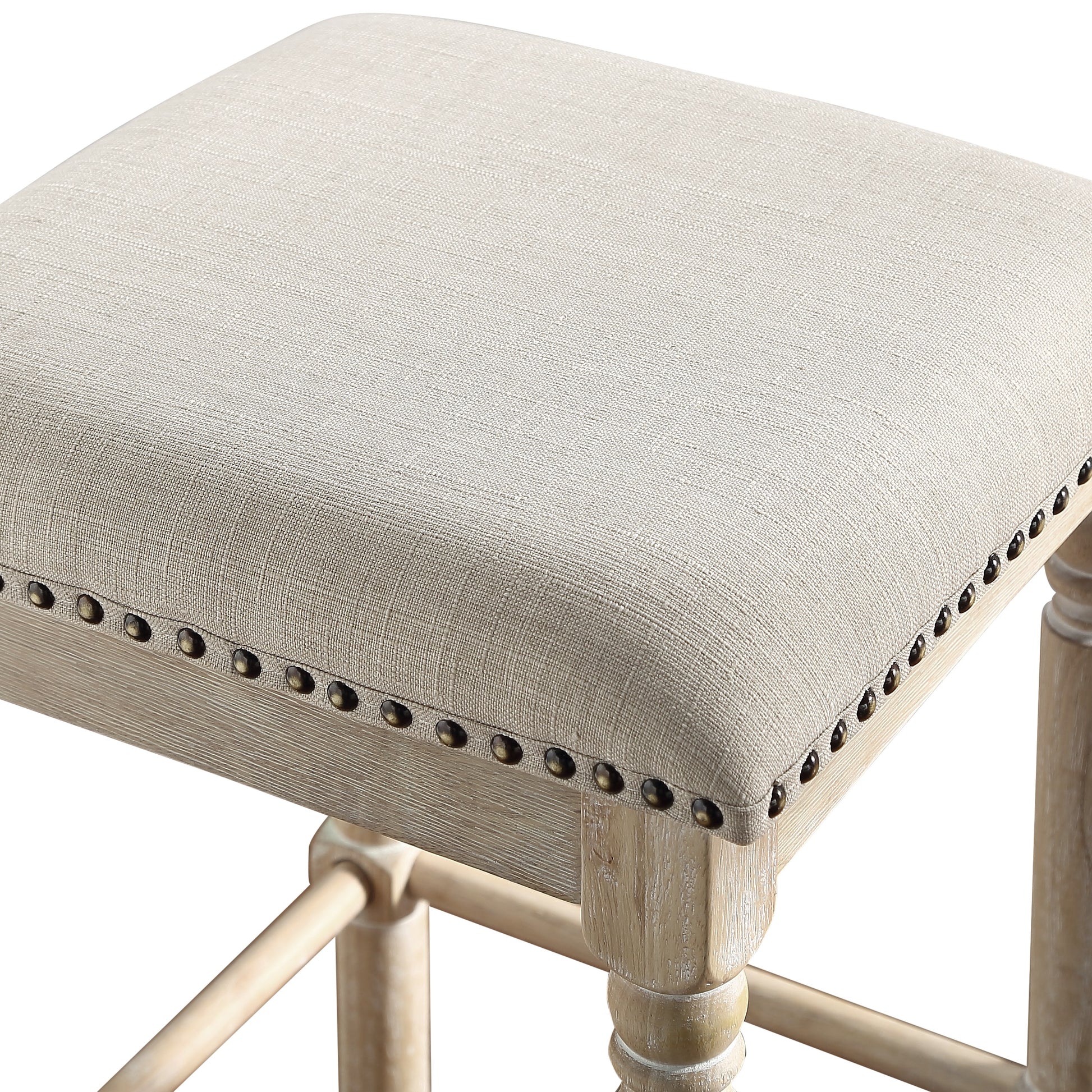 Cream fabric upholstered square stool with antique brass nailhead trim and distressed wood legs