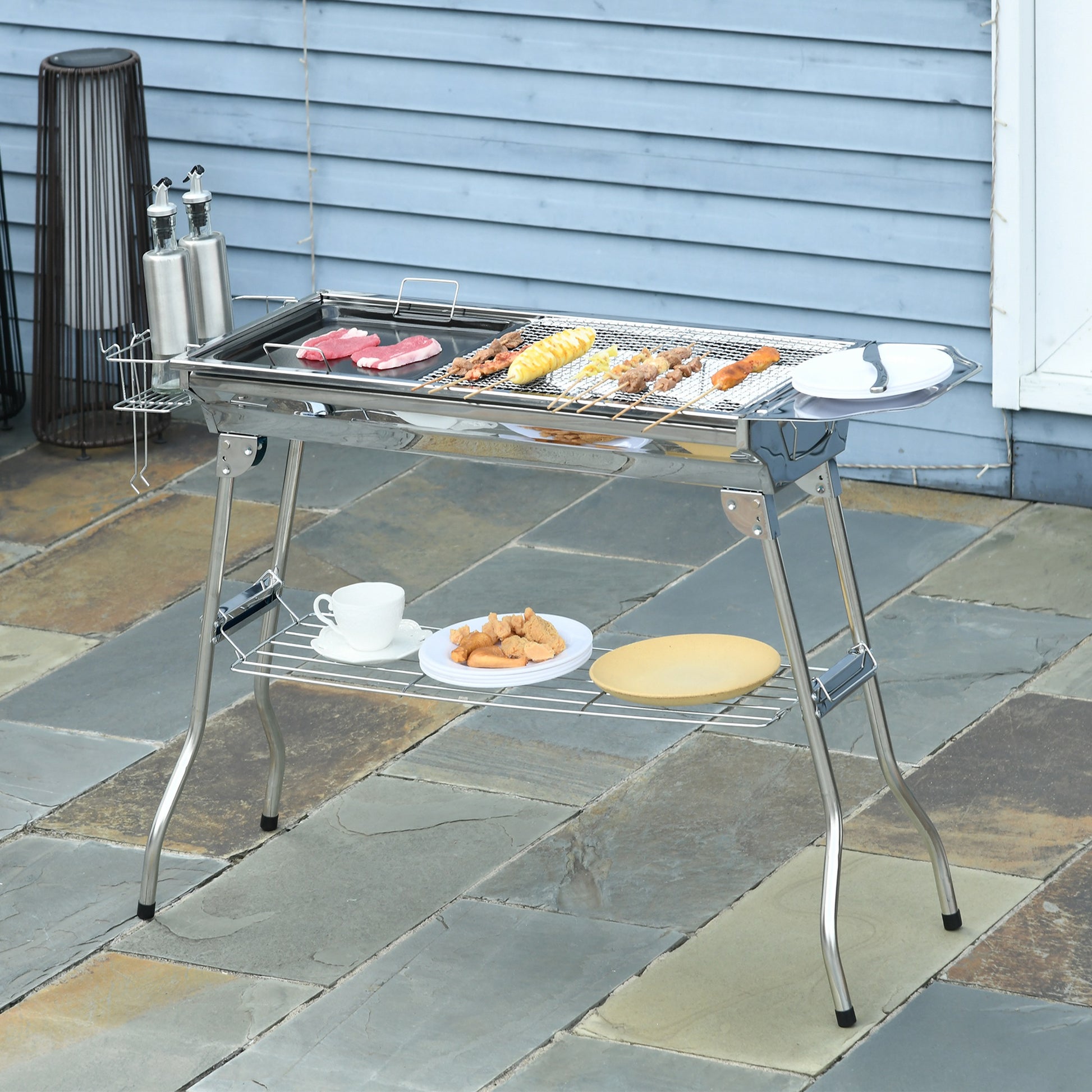Stainless steel portable grill with meat and corn on skewers