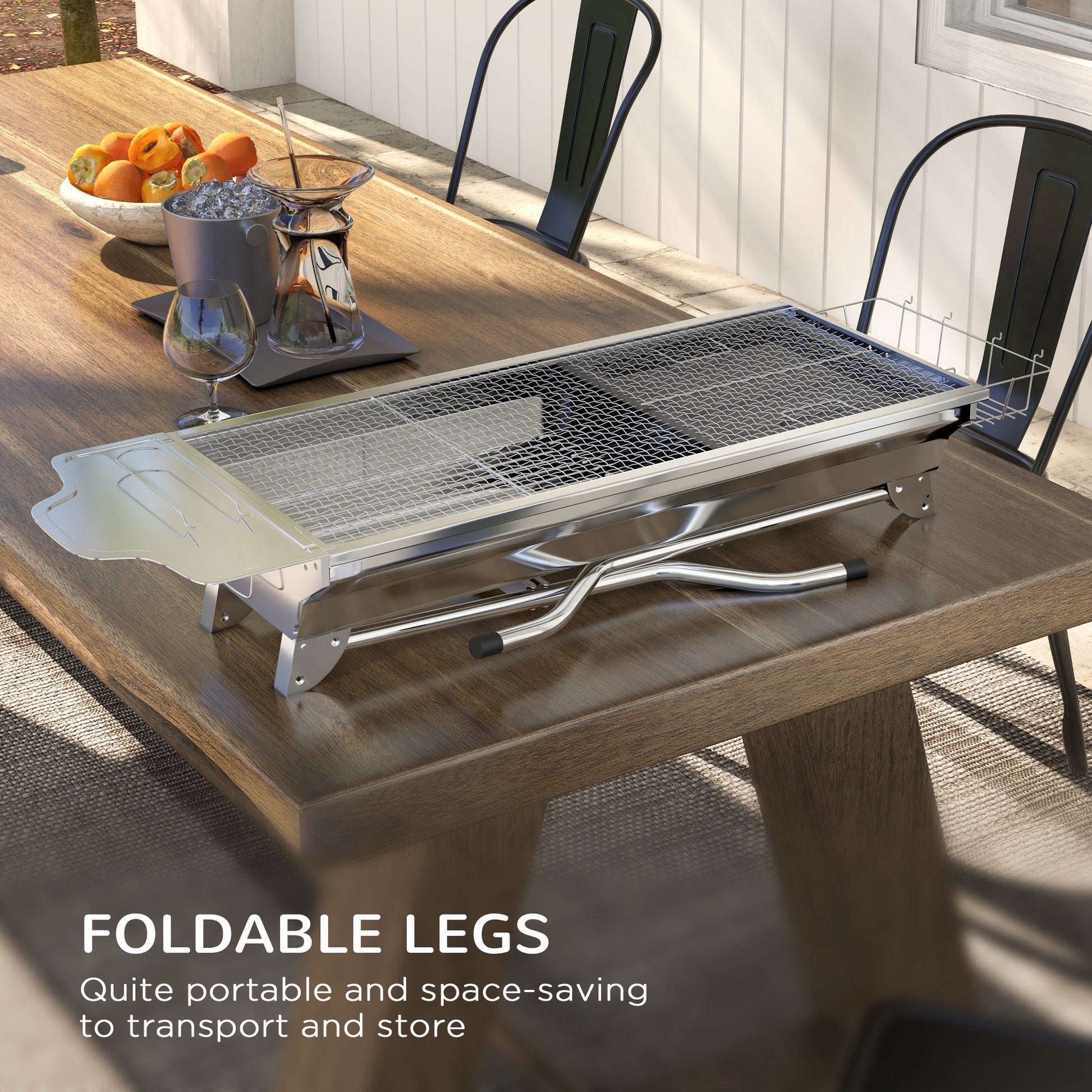 Compact stainless steel portable grill with foldable legs on a wooden table