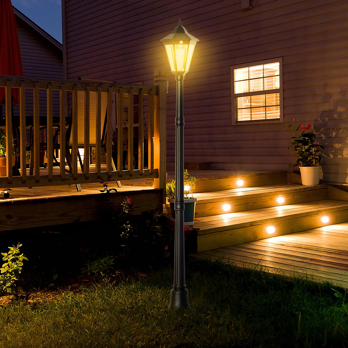 Black Victorianstyle garden lamp post with hexagonal lantern illuminated at dusk
