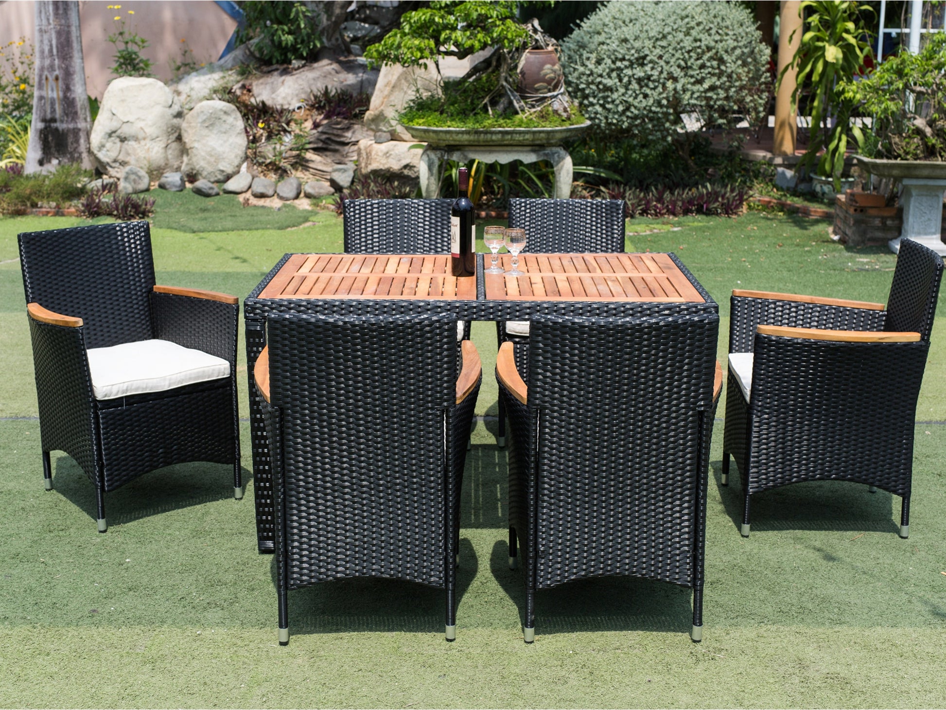 Black wicker dining set with wooden tabletop and white cushions perfect for outdoor entertaining