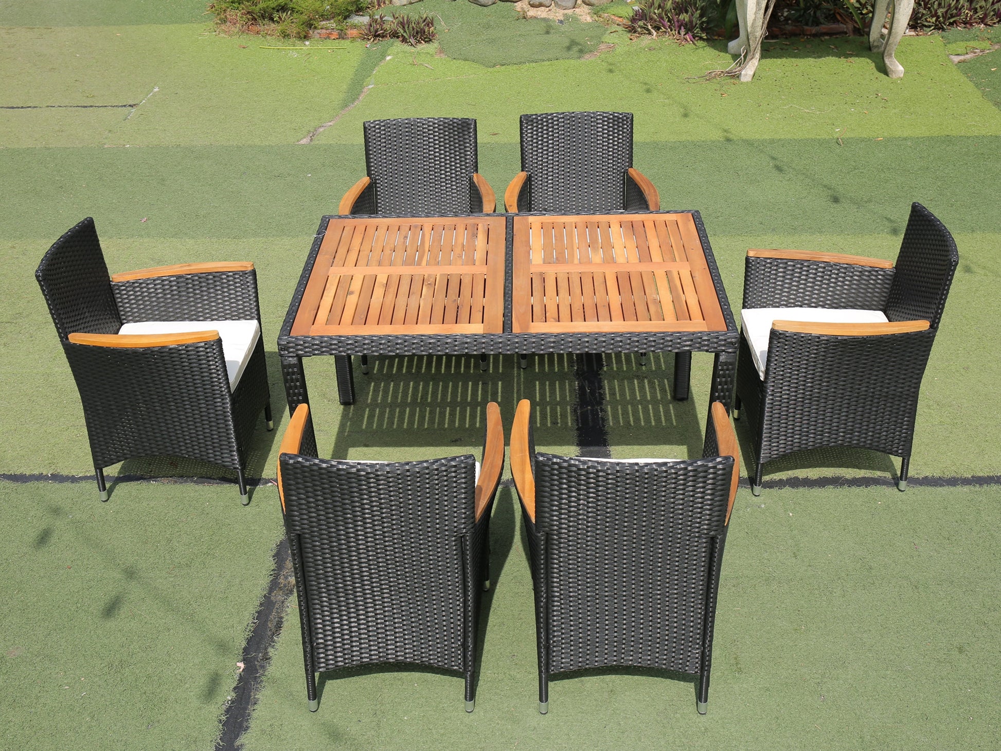 Woven black rattan patio dining set with wooden tabletop and white cushions
