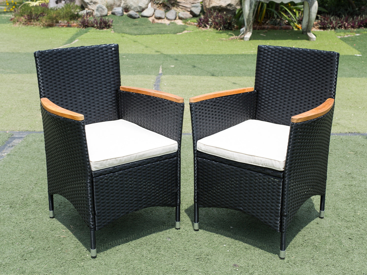 Two black wicker patio chairs with light beige cushions and wood armrests