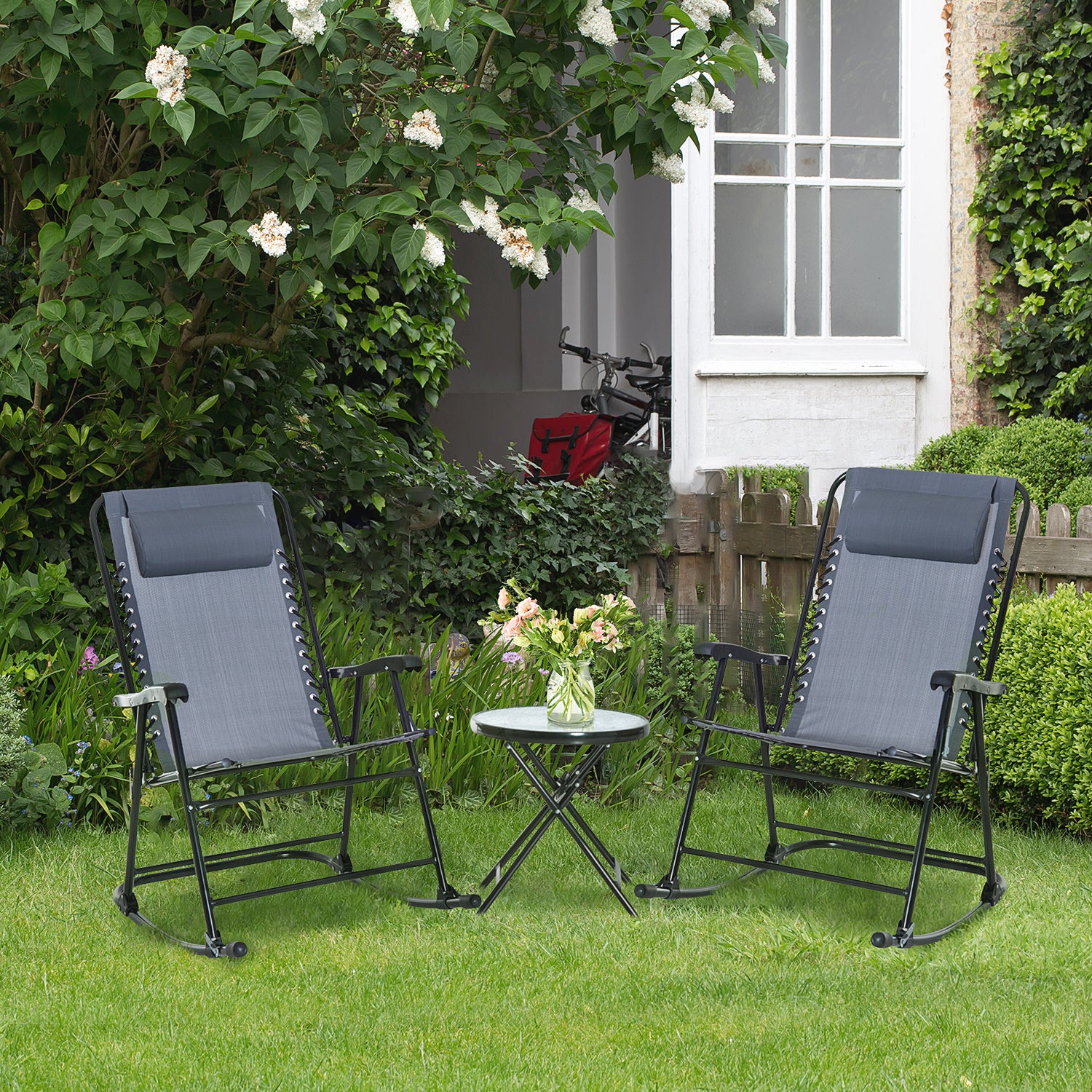 Two grey zero gravity chairs and a small glass table on a green lawn