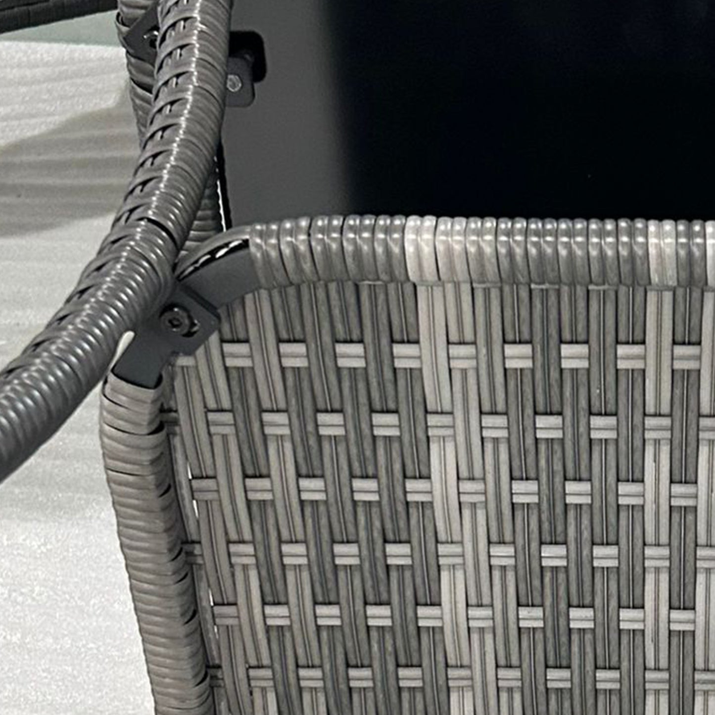 Closeup of a grey rattan patio chair weave with visible texture and dark frame detail