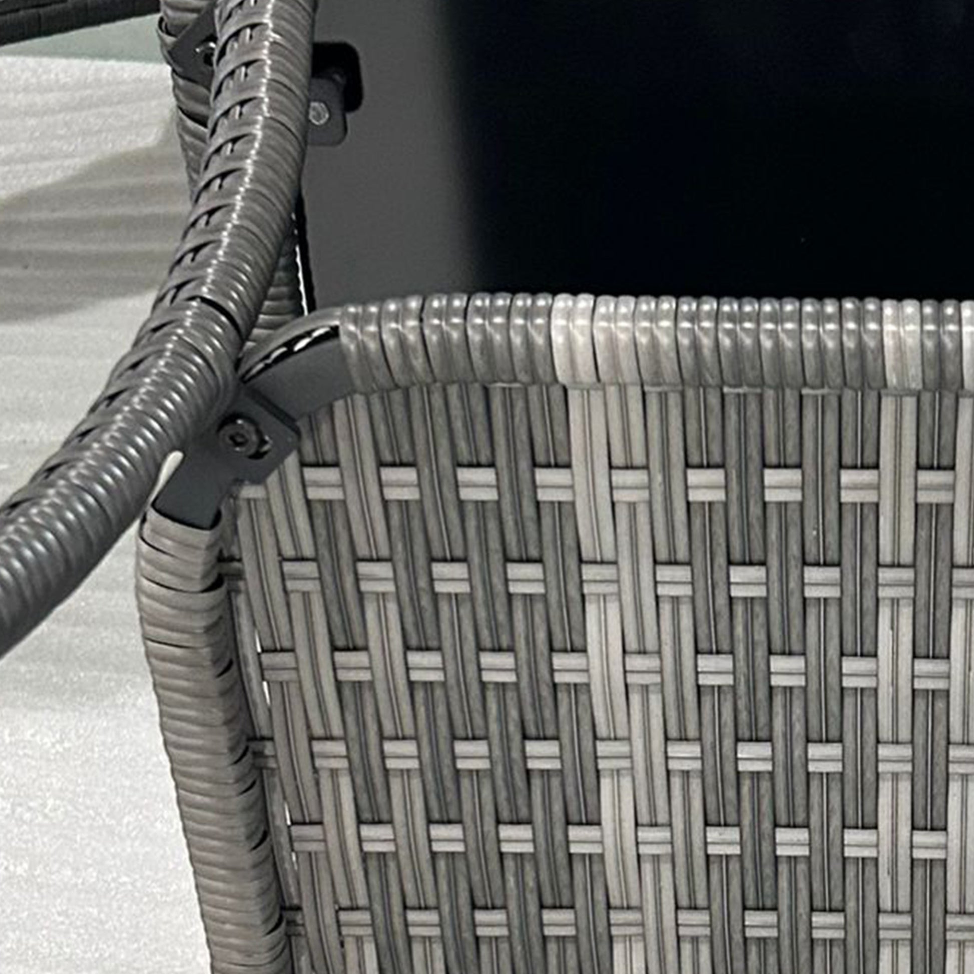 Closeup of a grey rattan patio chair weave with visible texture and dark frame detail