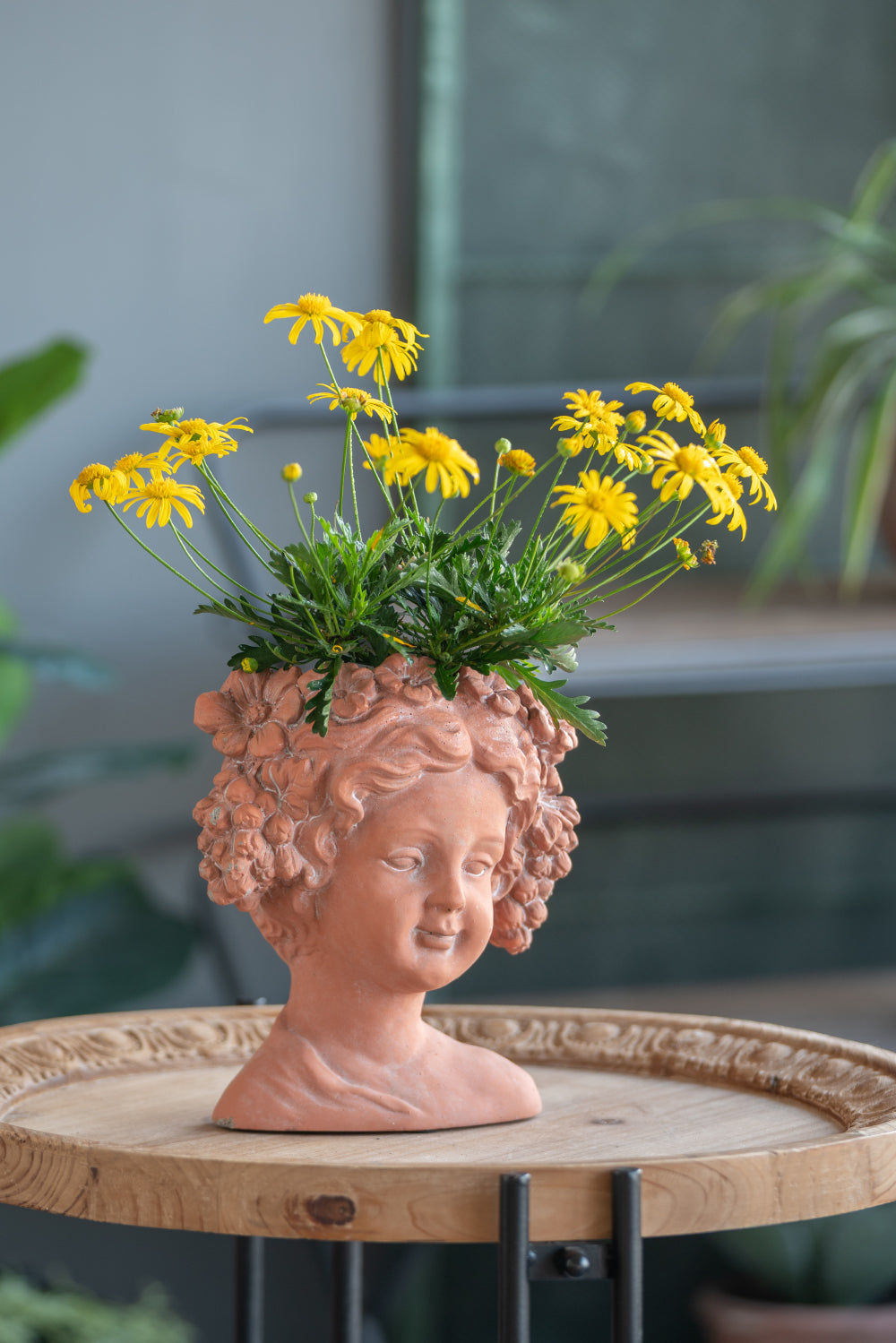 Terracotta cherub planter with blooming yellow daisies whimsical garden decor
