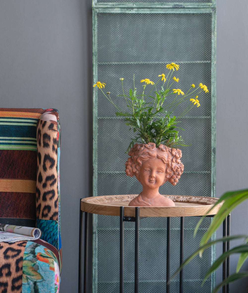 Terracotta planter shaped like a girls bust holding yellow flowers