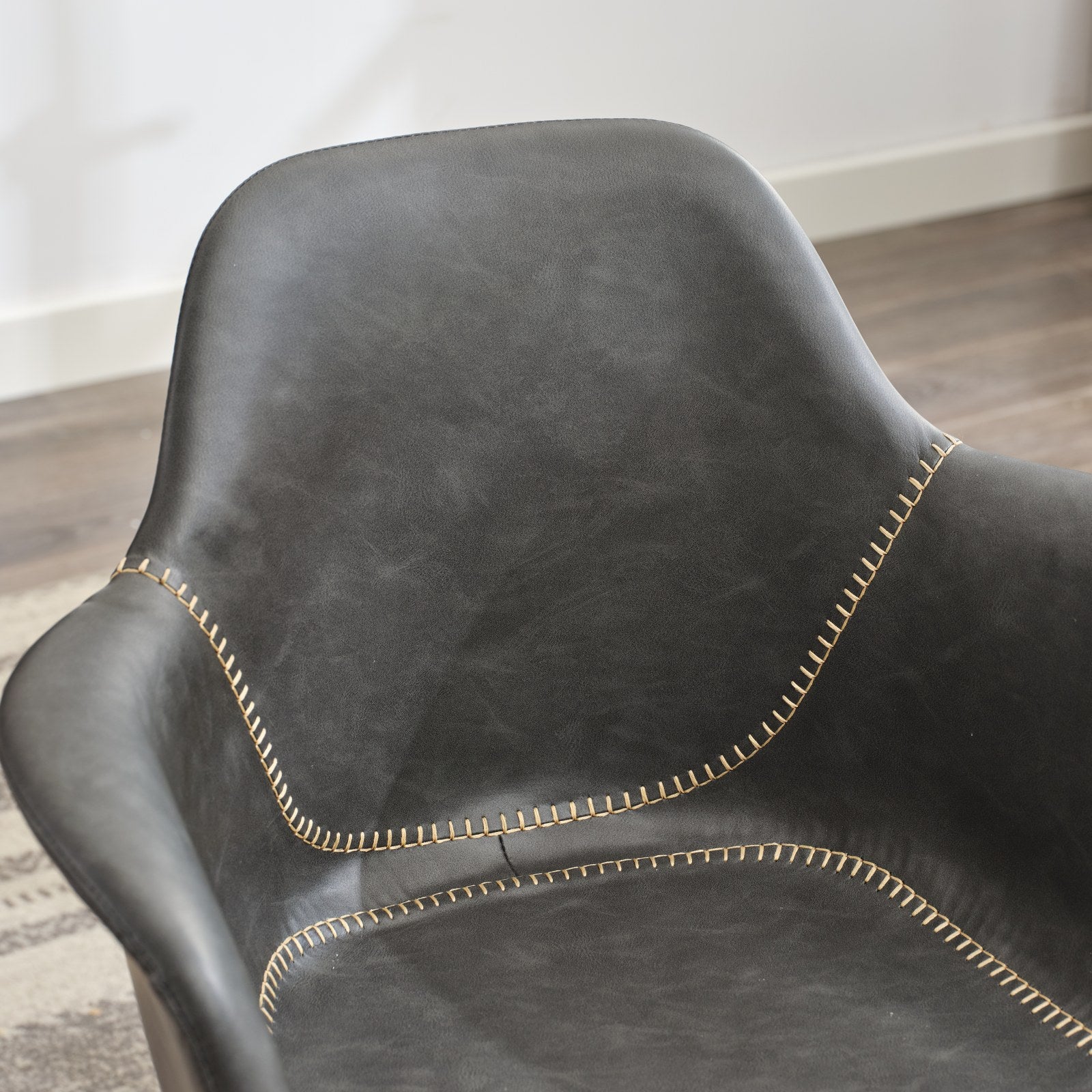 Dark grey faux leather accent chair with prominent cream contrast stitching detail